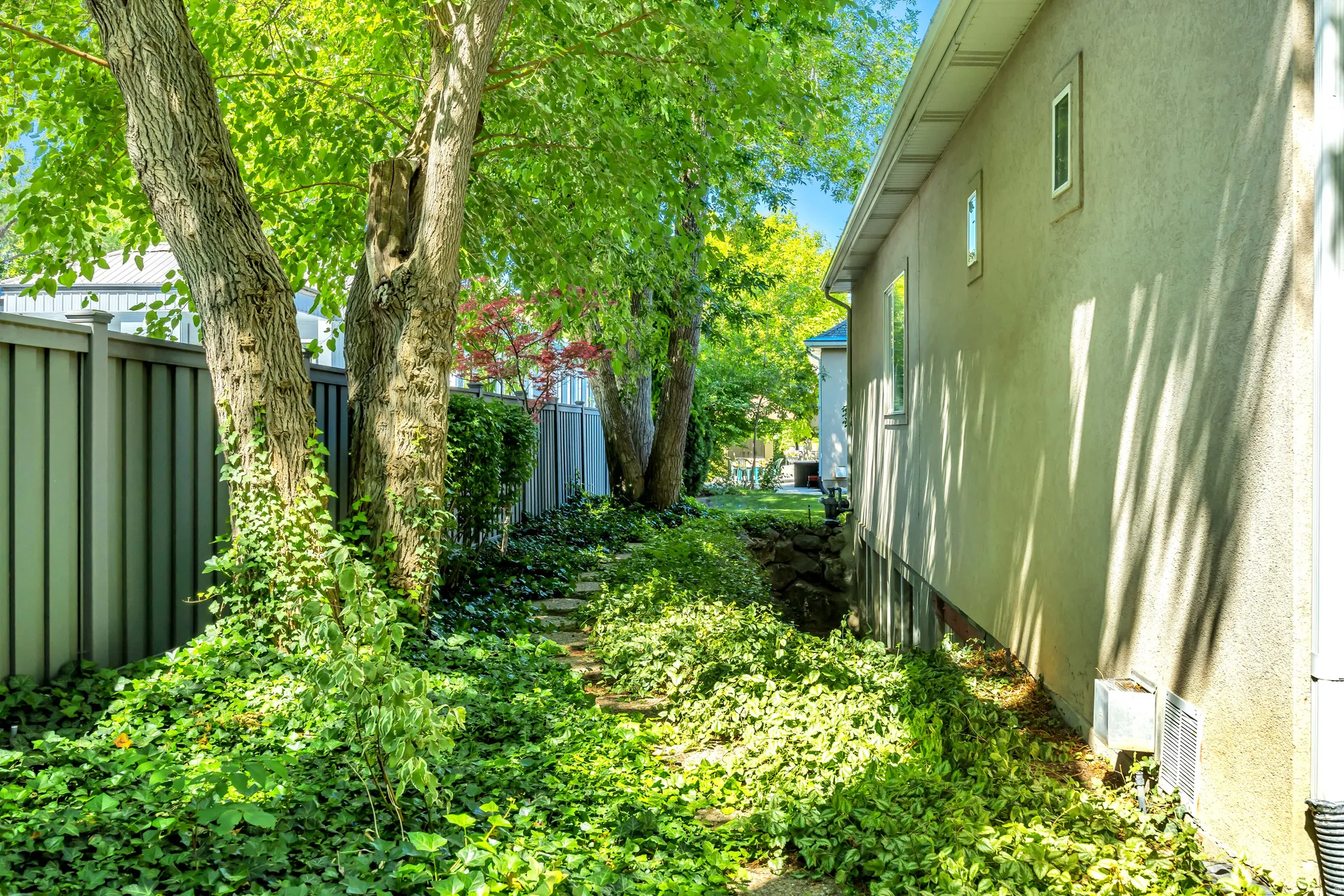 Lush green landscaping bordering a stucco exterior with multiple windows