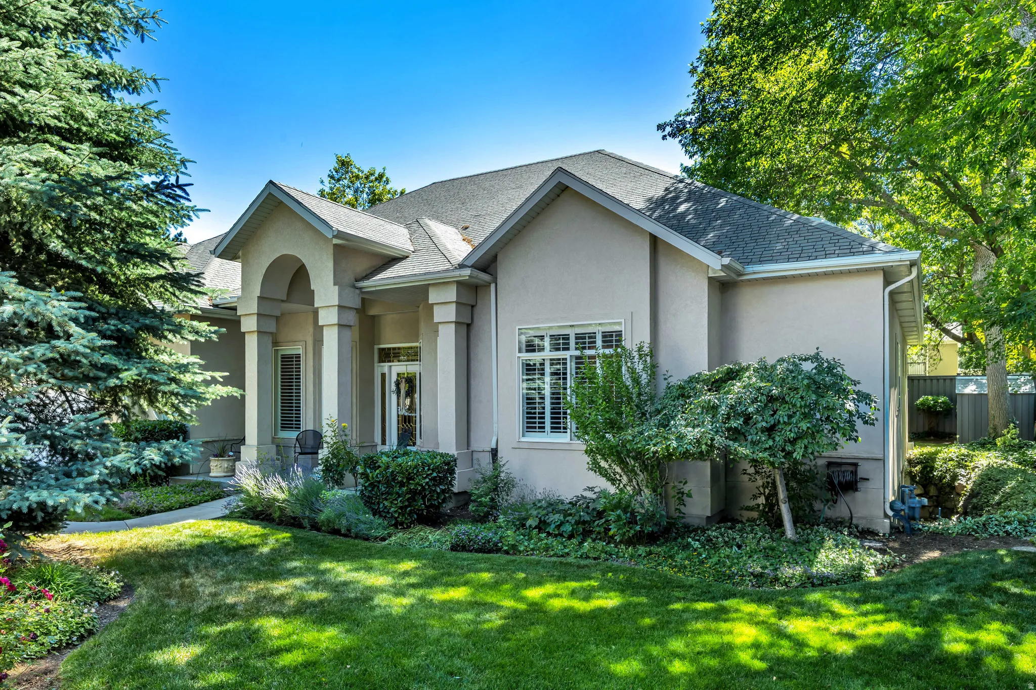 Stucco exterior featuring a covered entry with arched portico, column accents, and a gabled roofline