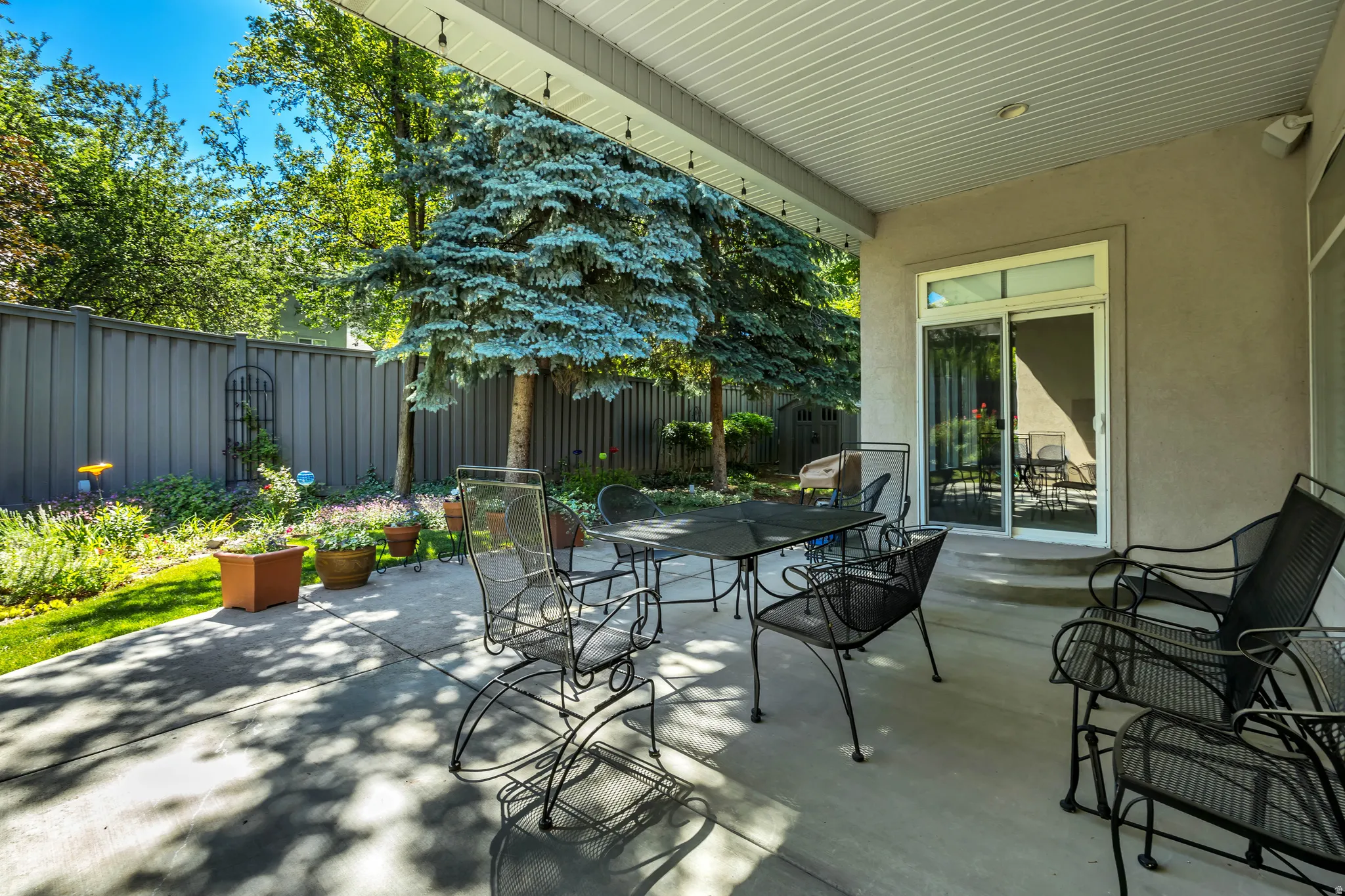 Expansive covered patio featuring a concrete surface, overhead lighting, and direct access to the interior via a sliding glass door