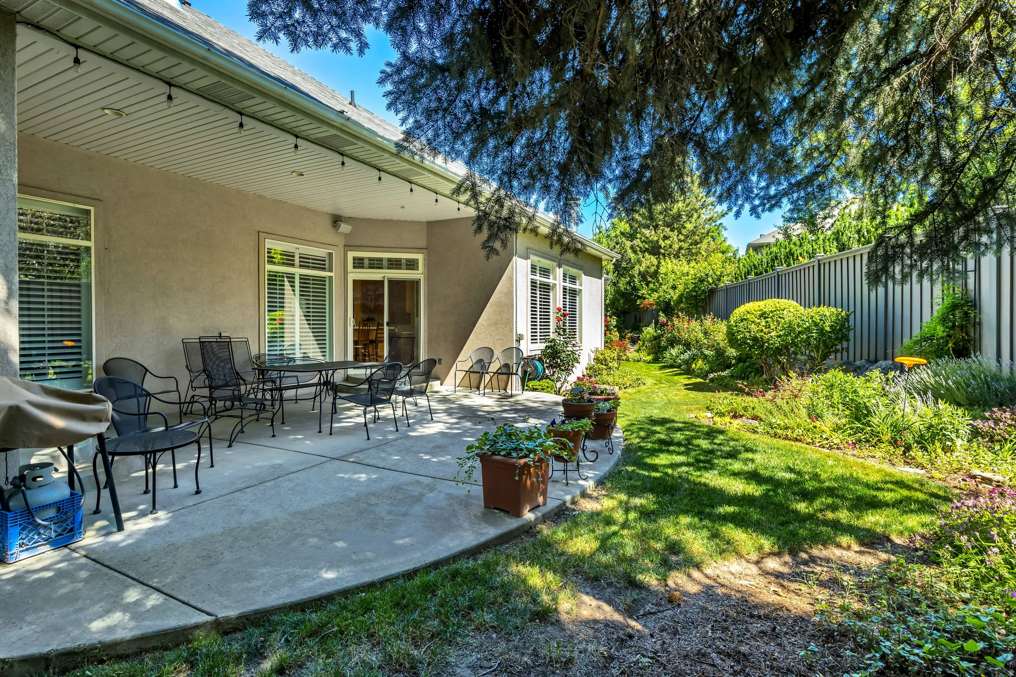 Private backyard with a covered patio, stucco exterior, multiple windows, and a sliding glass door