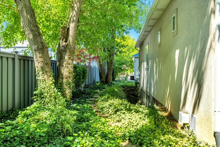 Lush green landscaping bordering a stucco exterior with multiple windows