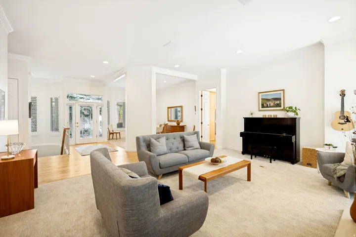 Sophisticated living room showcasing soaring ceilings with recessed lighting, light wood-finish flooring throughout, and an open floor plan