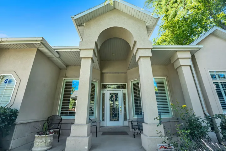 Arched entryway featuring a decorative glass door, stucco exterior, multiple bay windows with plantation shutters