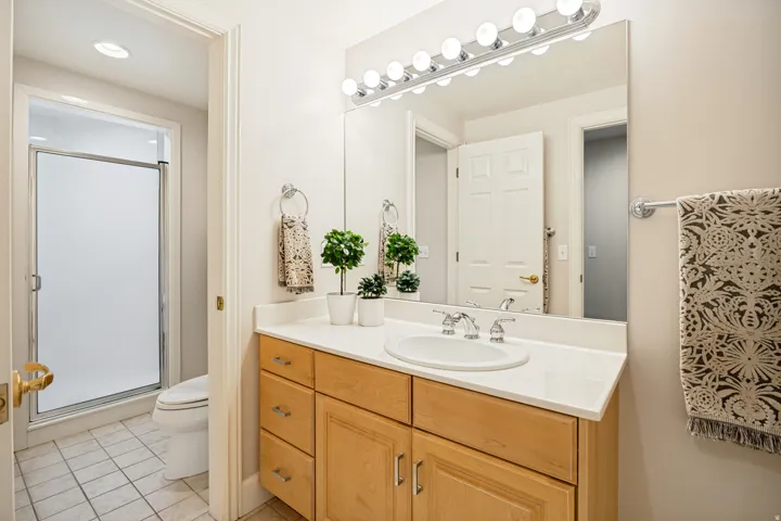 Jack and Jill bathroom featuring a wood-finish vanity with a light-toned countertop, an integrated sink with a chrome faucet, and a large wall-mounted mirror