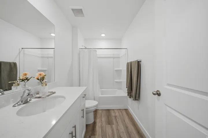 White vanity with integrated sink and chrome fixtures, framed by a large mirror