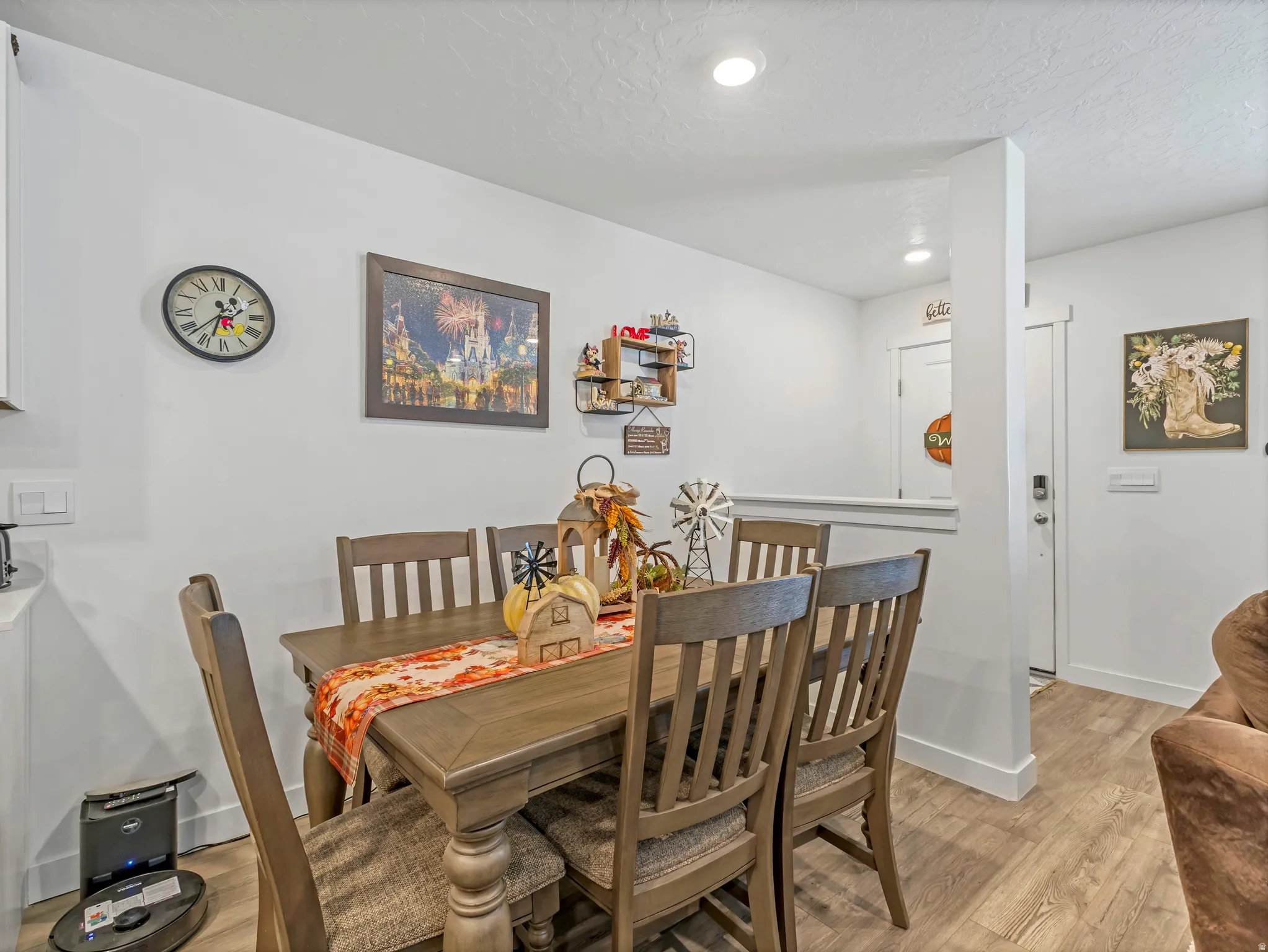 Recessed ceiling lights illuminate the dining area featuring wood-finish flooring and white baseboards