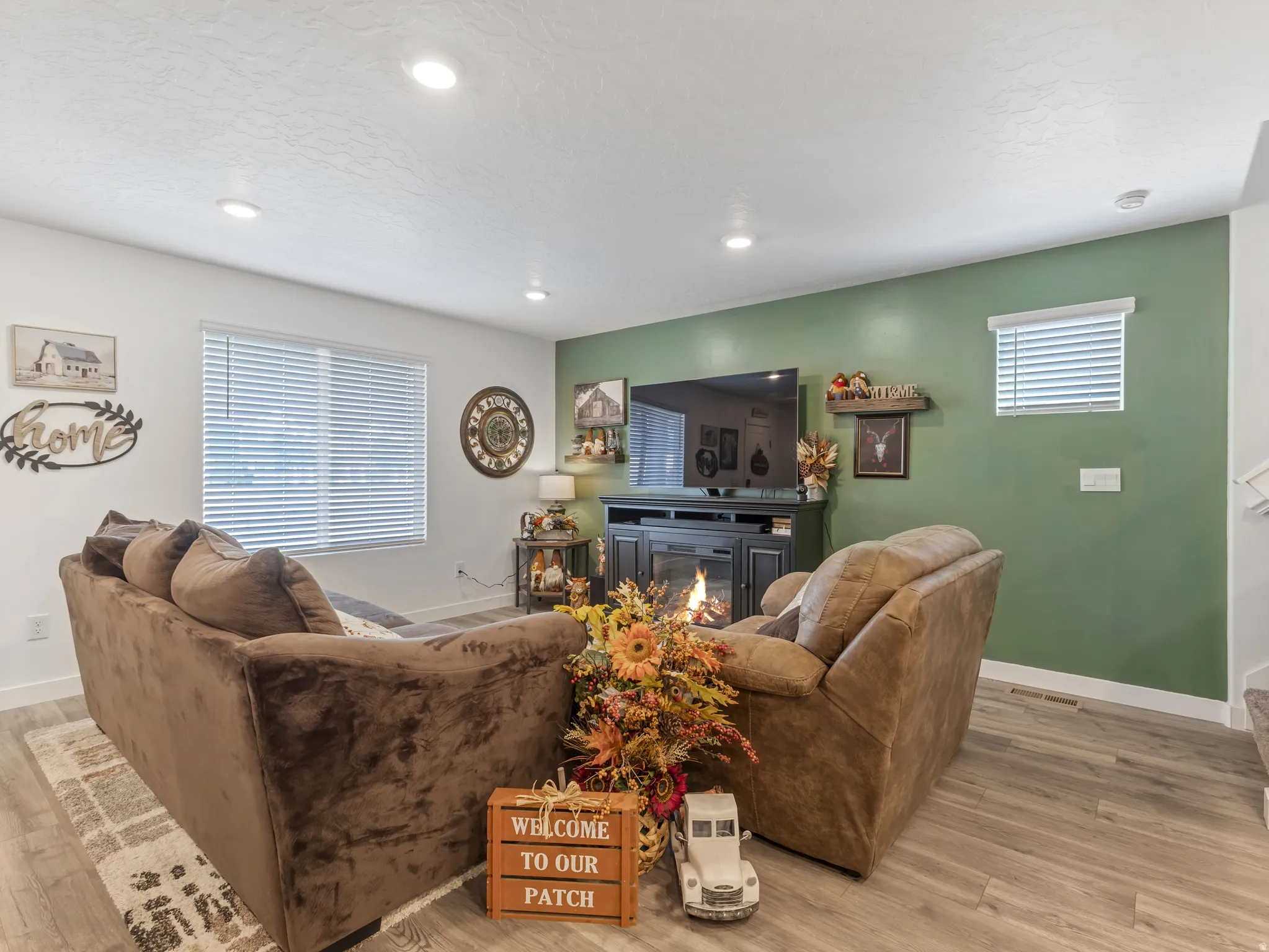 Spacious living area featuring wood-finish flooring, recessed lighting, and large windows with blinds