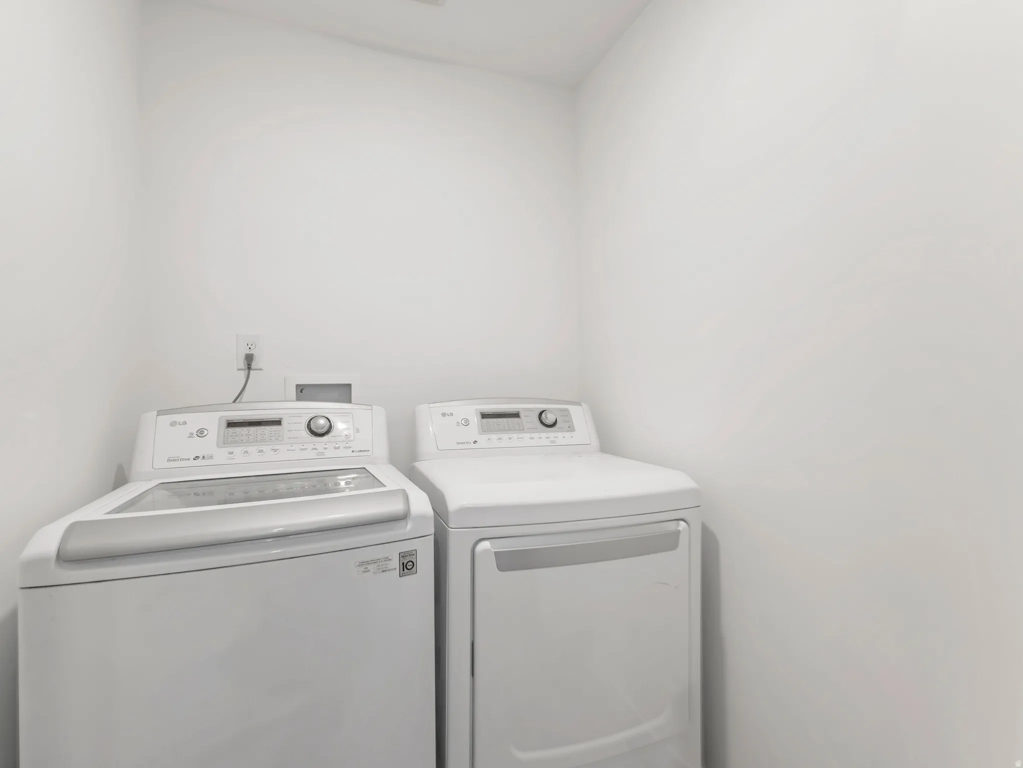 Dedicated laundry room featuring side-by-side washer and dryer with stainless steel finishes, control panels with digital displays, and ample countertop space above for folding and sorting