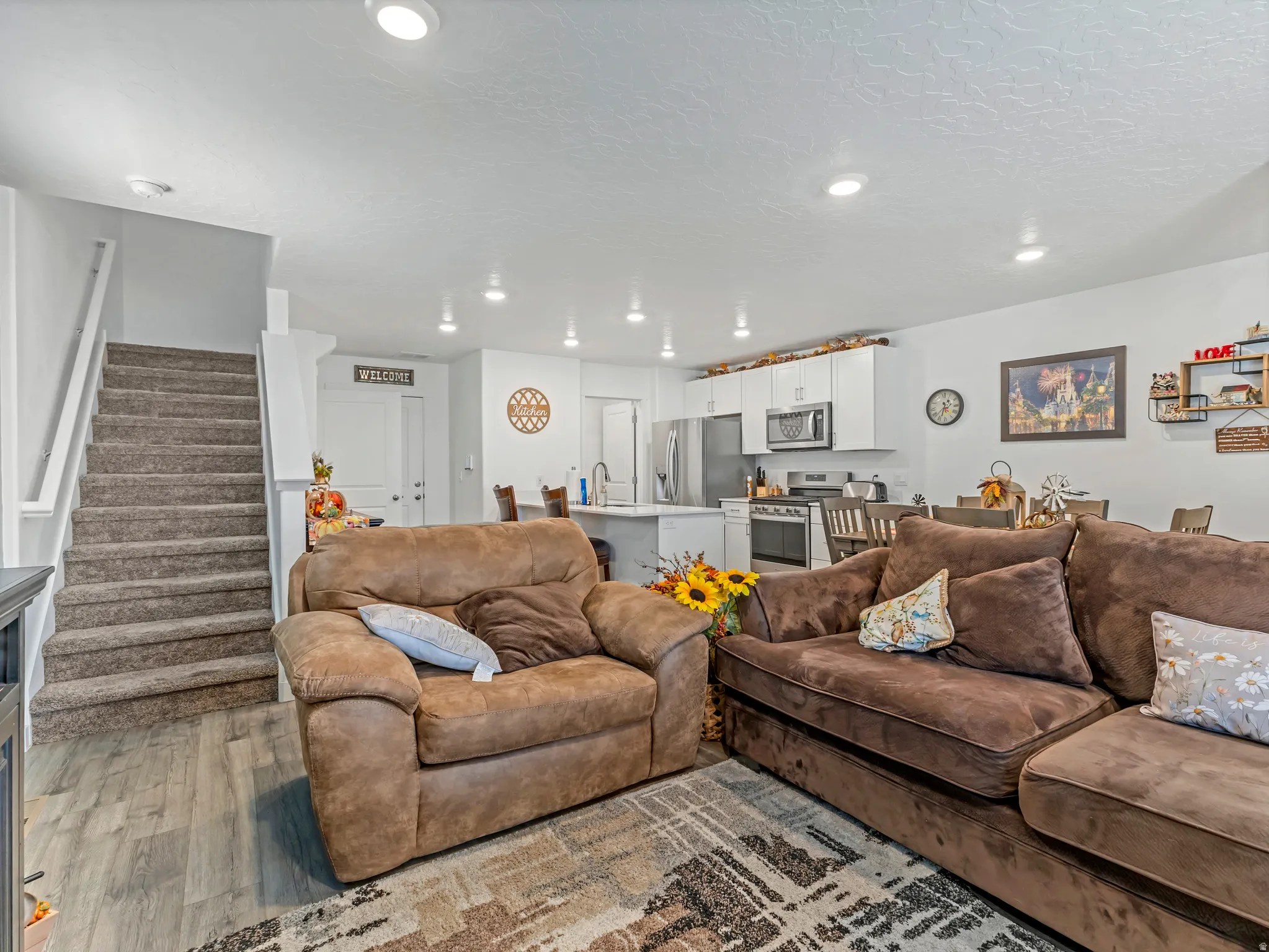 Open-concept living space featuring wood-finish flooring, recessed lighting, and a neutral color palette