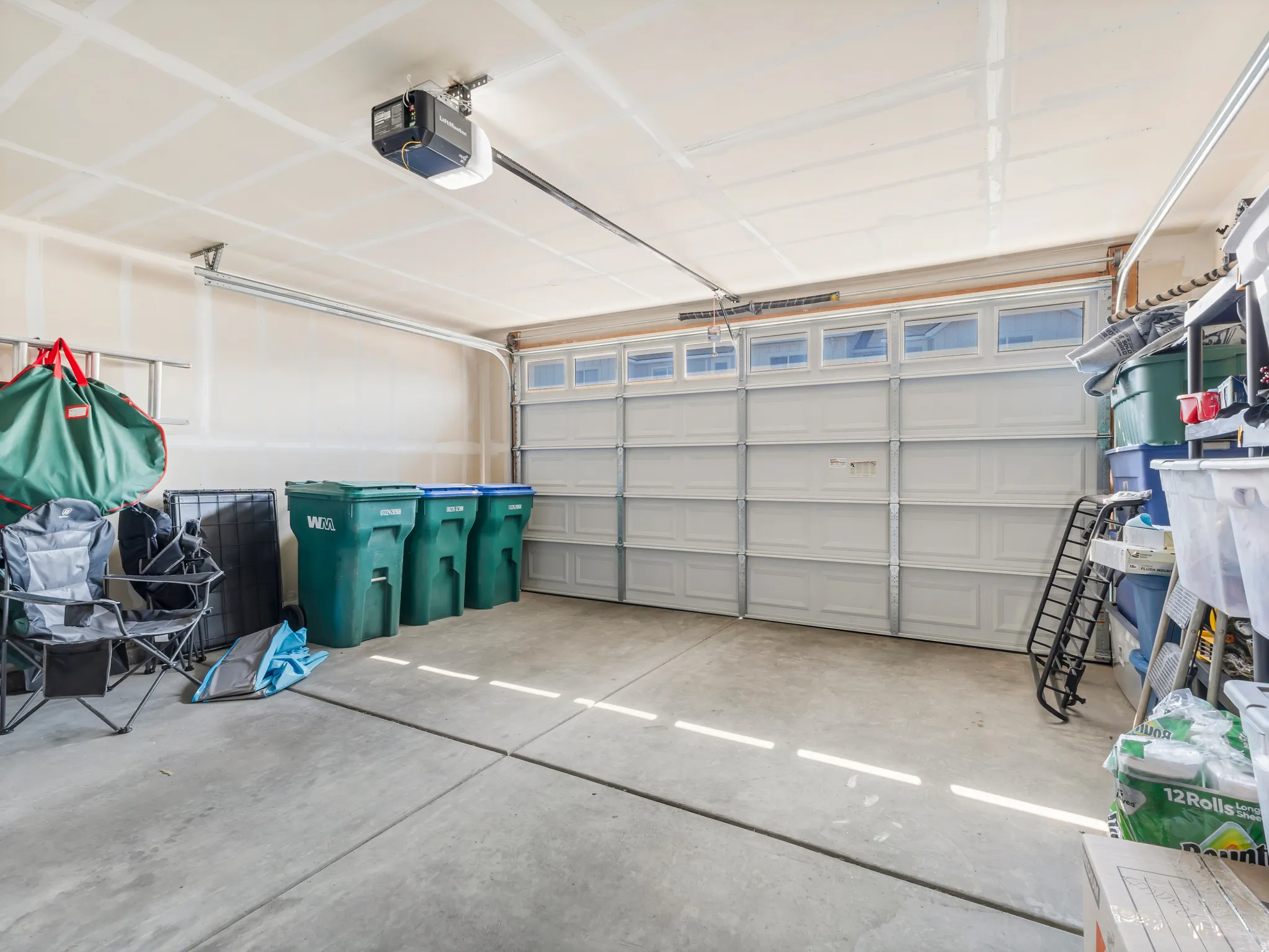 Spacious garage featuring a concrete floor, overhead lighting, and an automatic garage door opener