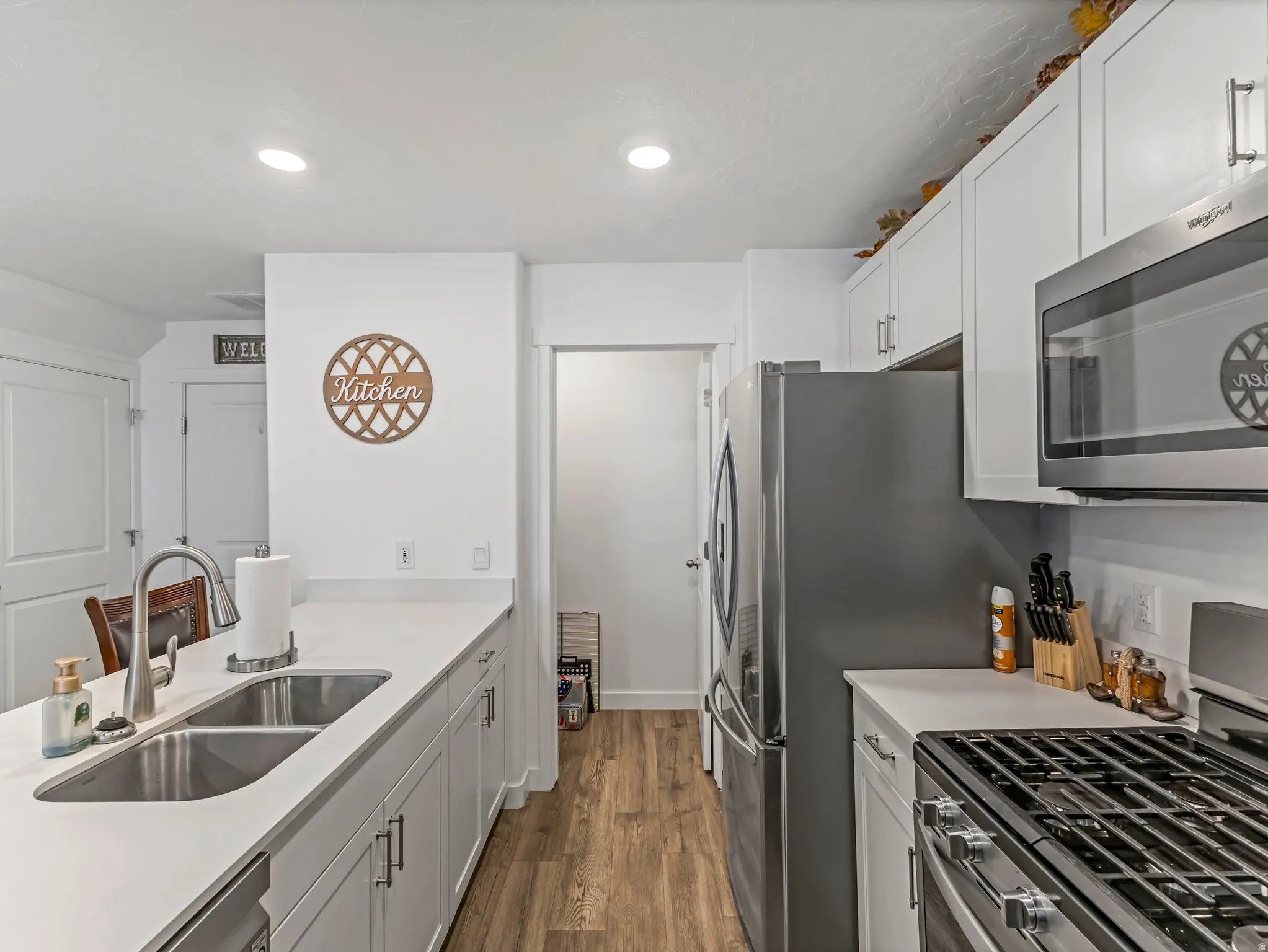 Modern kitchen featuring white cabinetry, light countertops, wood-finish flooring, stainless steel appliances, and recessed lighting