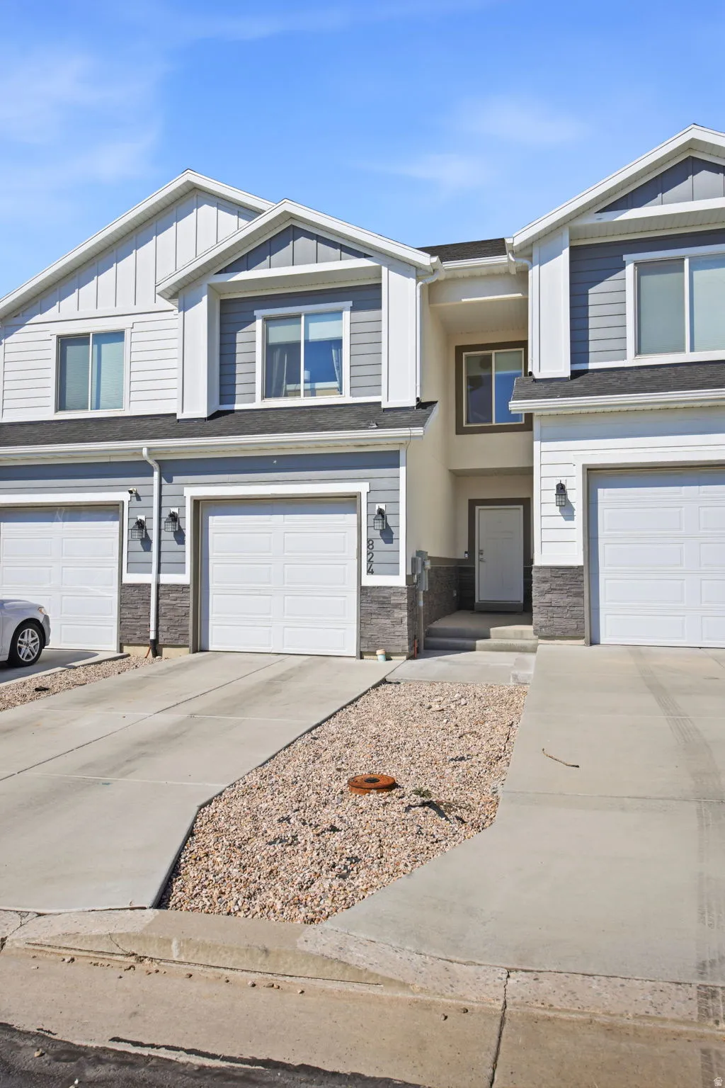 Modern two-story townhome featuring a clean front elevation with mixed siding and stone accents, two-car garage with white panel doors, and a gabled roofline with architectural detailing