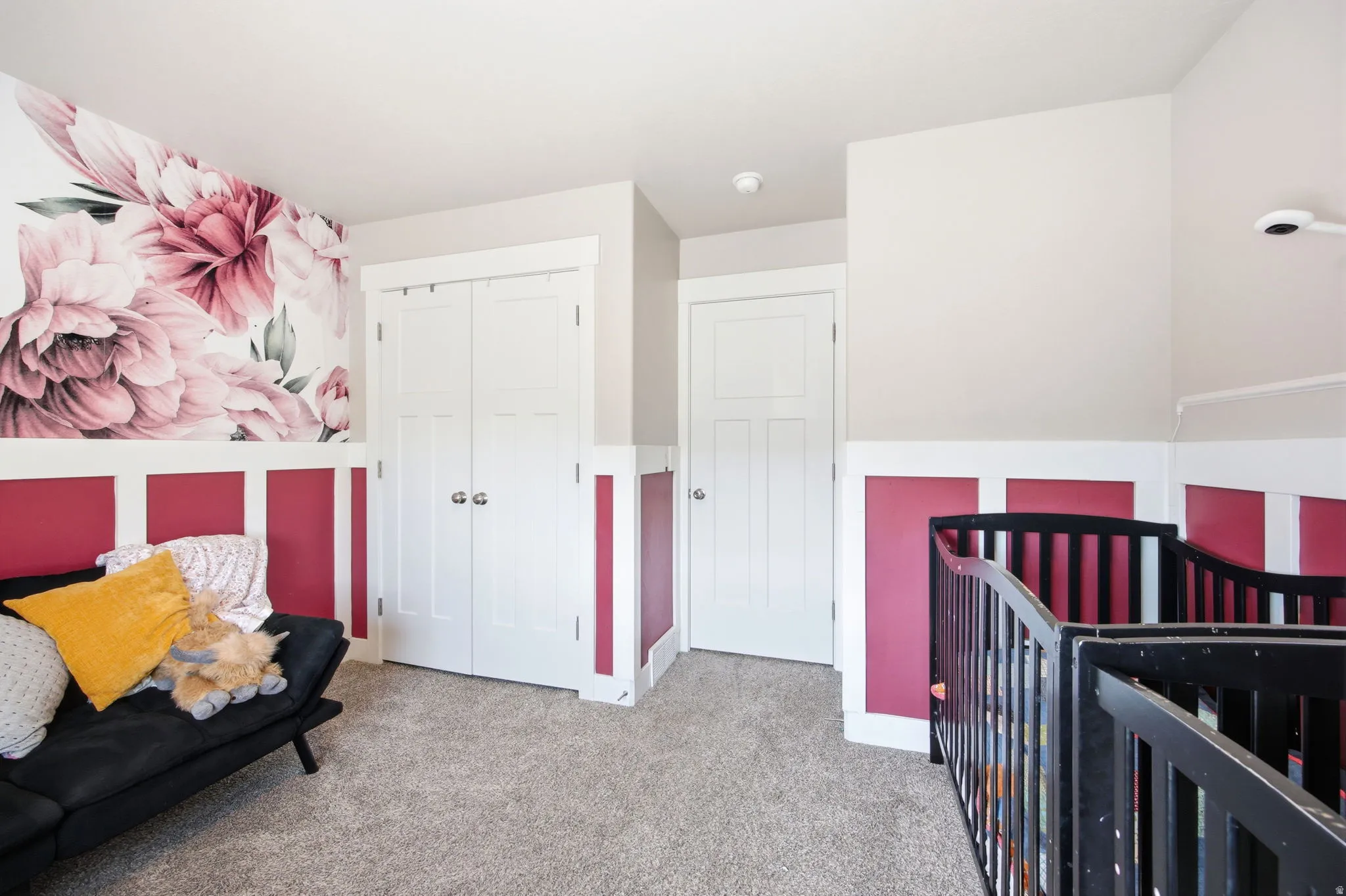 Versatile bedroom suite featuring soft carpet flooring, bold pink and white color-blocked wall paneling, and ample closet storage with dual white panel doors