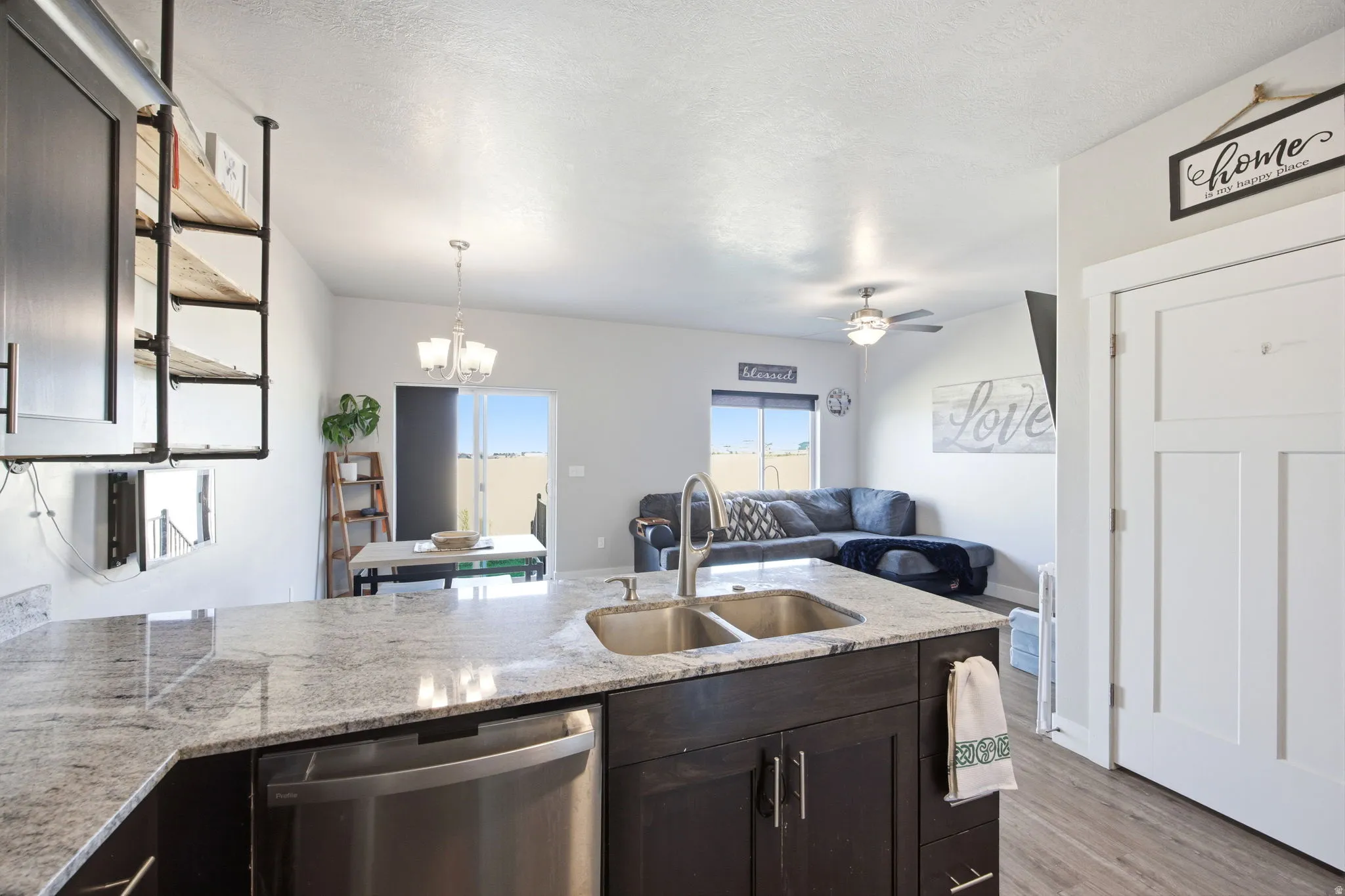 Kitchen island featuring a double basin stainless steel sink, a stainless steel dishwasher, and a light-toned countertop