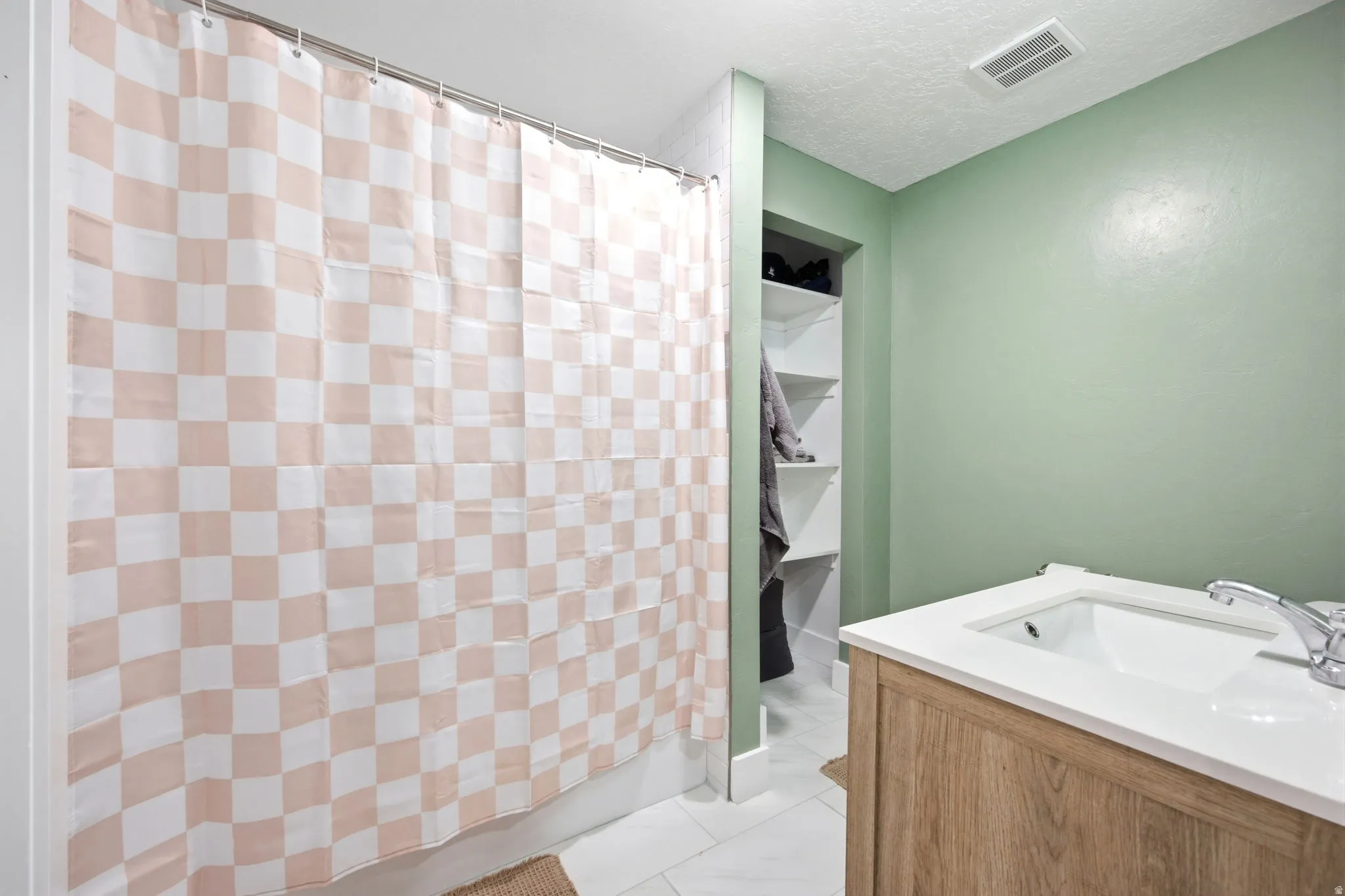 Spa-inspired primary bathroom featuring a soaking tub with wood-finish vanity cabinetry, soft-close fixtures, and crisp white countertop surfaces
