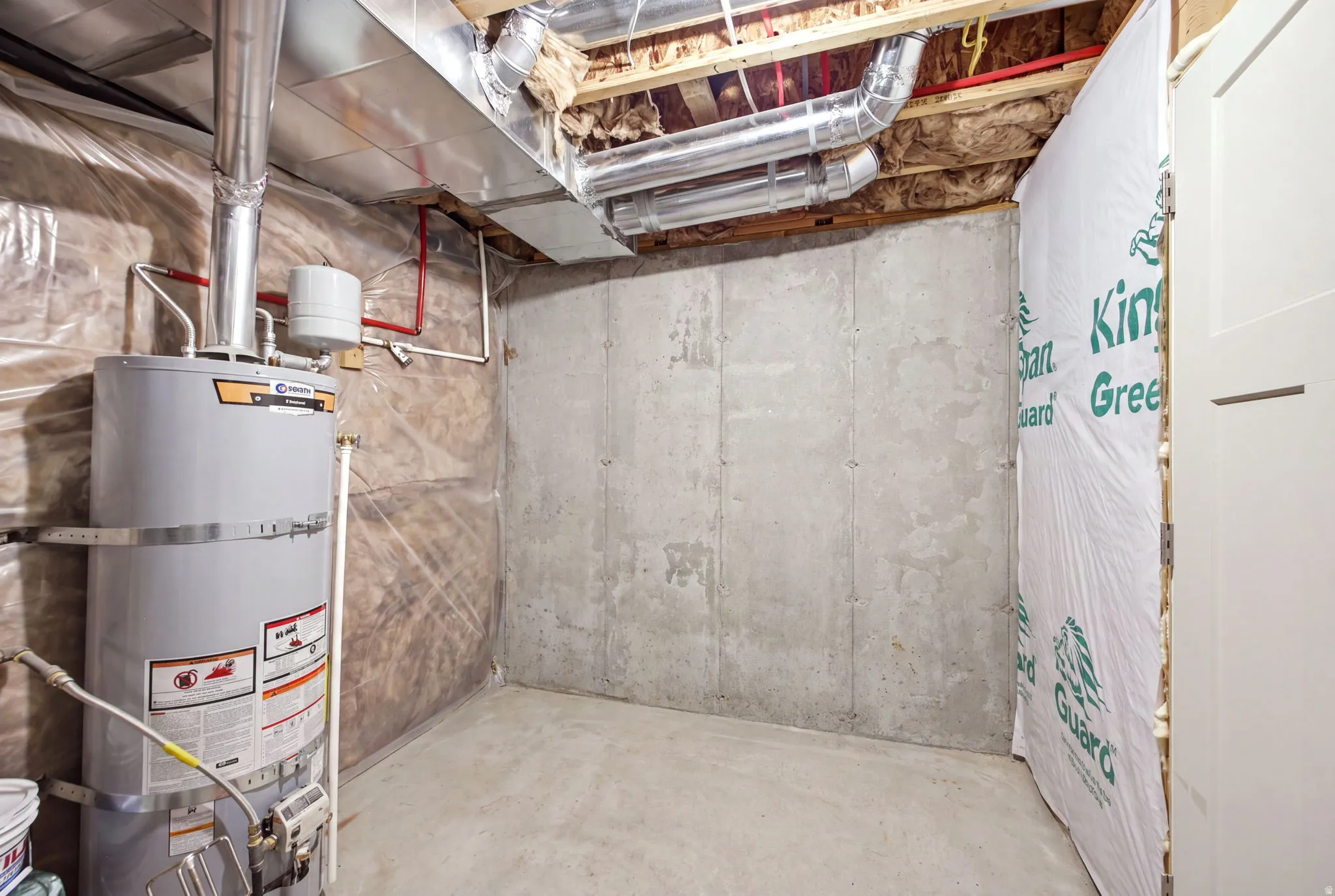 Utility room featuring concrete flooring, exposed ceiling infrastructure with mechanical systems, and a gas water heater with temperature and pressure relief valve