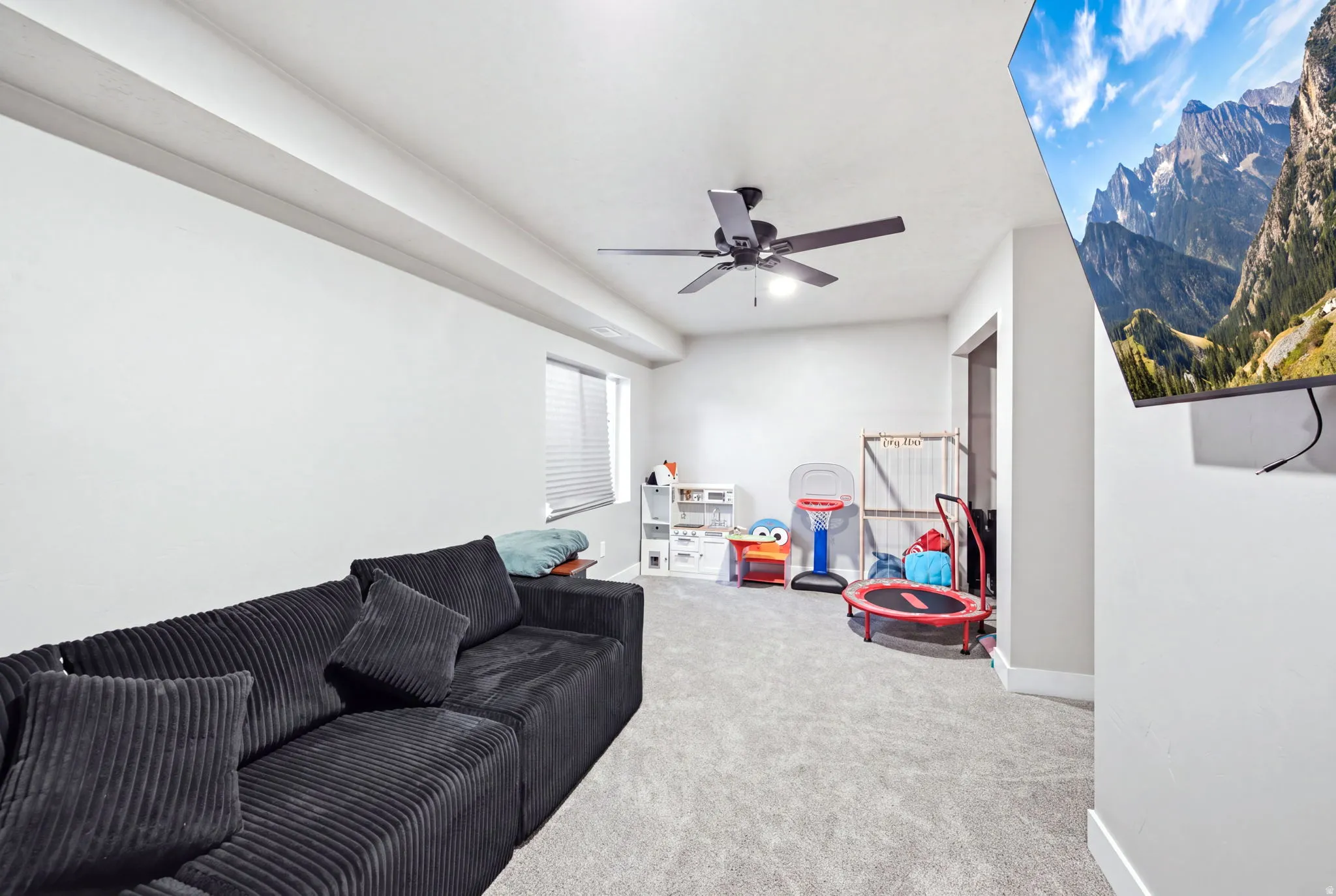 Spacious recreation room featuring polished concrete flooring, exposed beam ceiling detail, and ceiling fan
