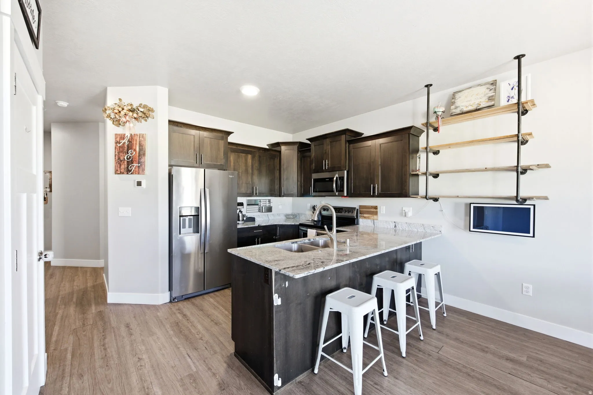 Modern kitchen featuring dark cabinetry with stainless steel appliances, white quartz countertops, and a substantial island with seating for multiple guests