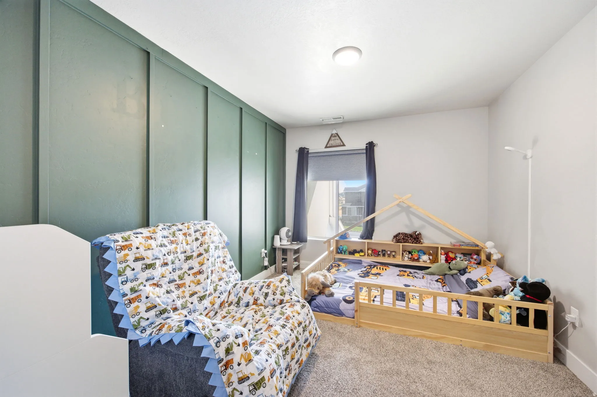 Spacious bedroom featuring floor-to-ceiling sliding glass doors with frosted panels, carpeted flooring, and ample natural light