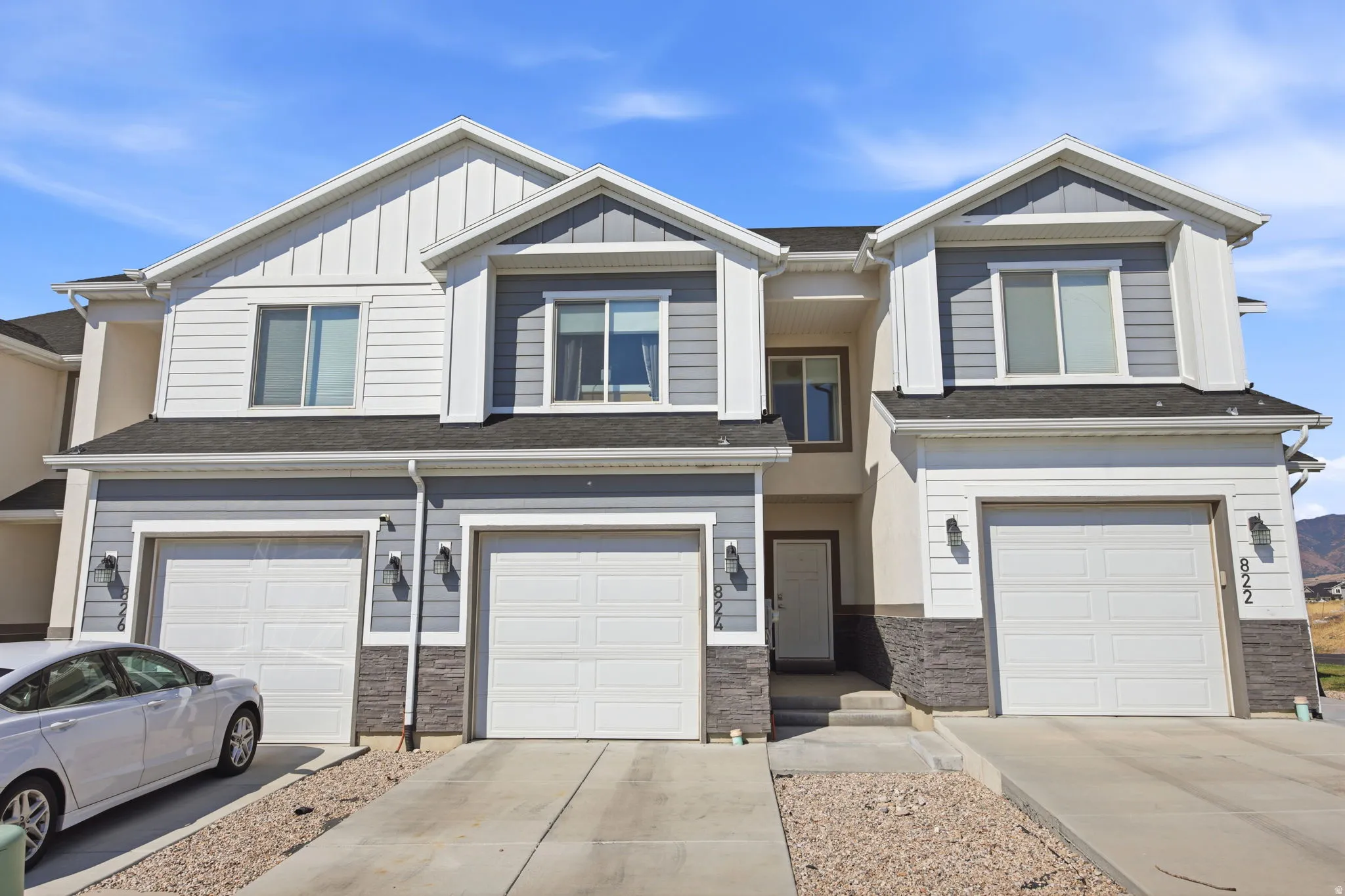 Modern two-story townhome featuring a clean, contemporary facade with mixed siding and stone accents