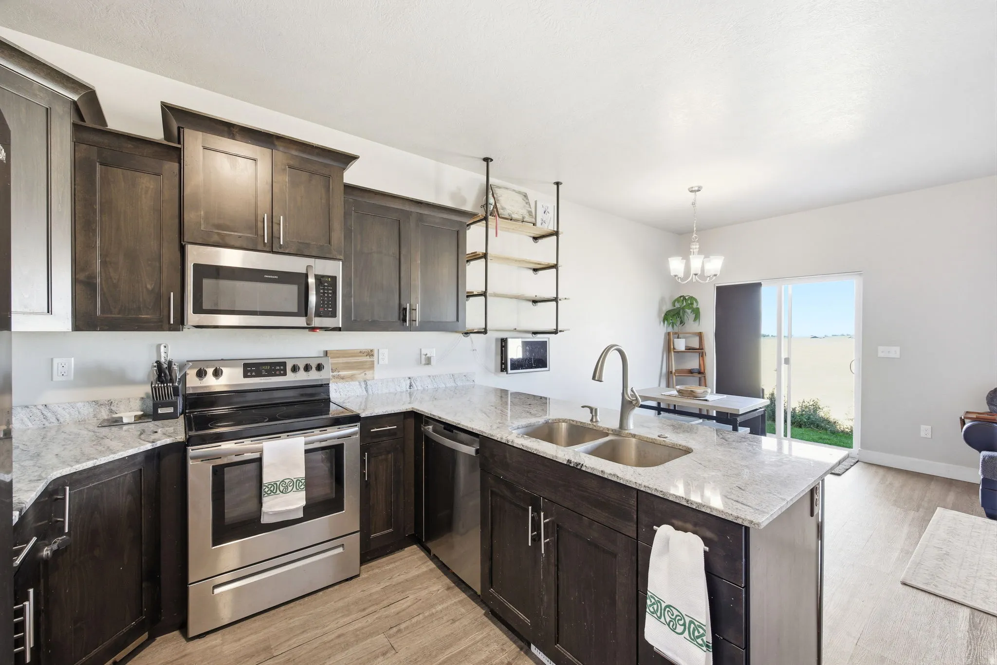 Modern kitchen featuring dark wood cabinetry with stainless steel appliances, including a gas range and built-in microwave