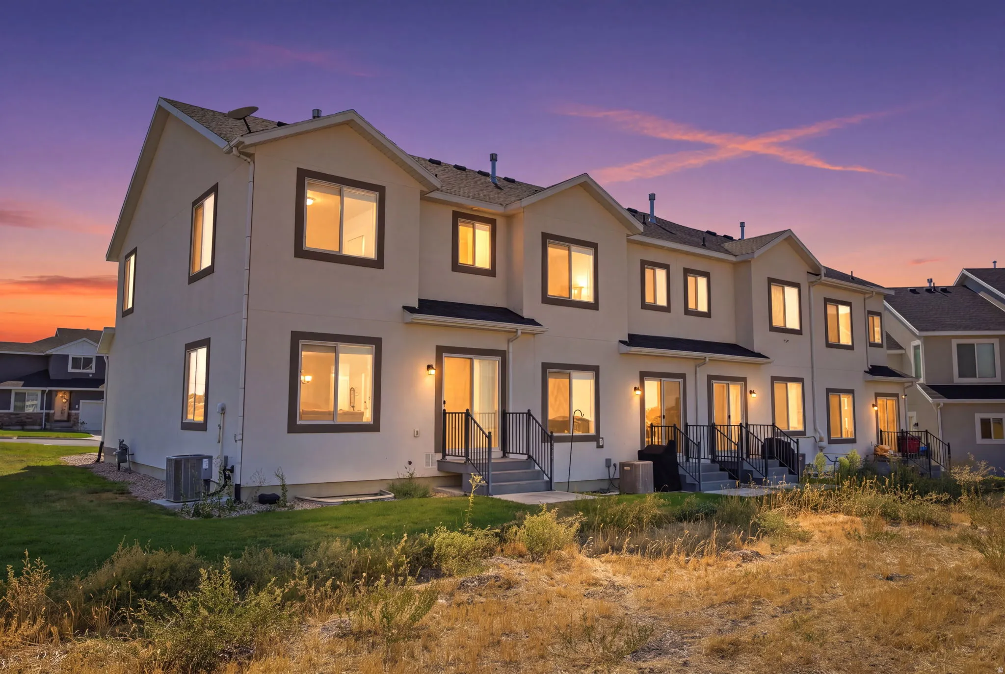 Modern coastal residence showcasing a clean-lined exterior with stucco cladding, multiple large casement windows with warm interior lighting, and a tiered roofline