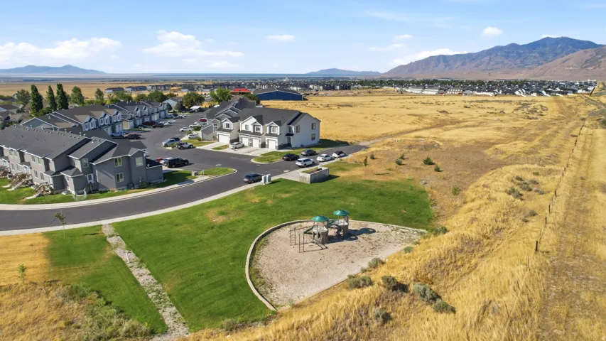 Expansive residential lot showcasing manicured lawn, circular hardscaped patio with playground equipment, and curved stone pathway