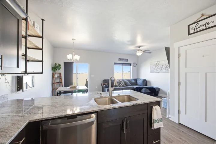 Kitchen island featuring a double basin stainless steel sink, a stainless steel dishwasher, and a light-toned countertop