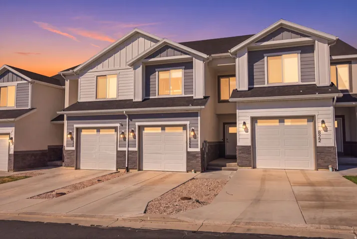 Modern townhome exterior featuring gray siding, white trim, and stone accents