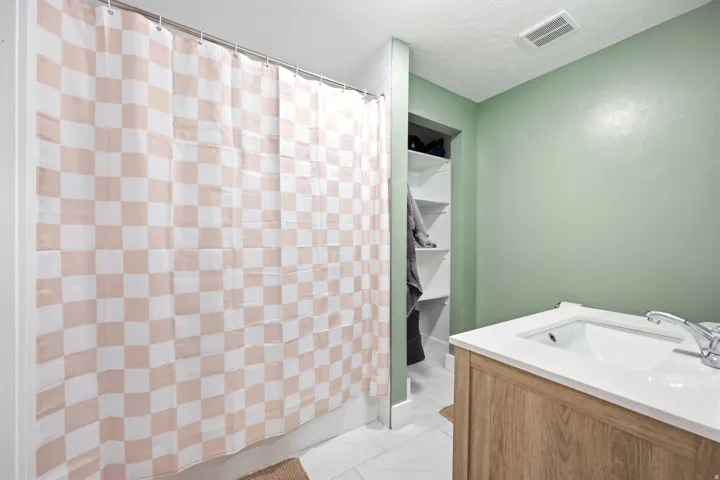 Spa-inspired primary bathroom featuring a soaking tub with wood-finish vanity cabinetry, soft-close fixtures, and crisp white countertop surfaces