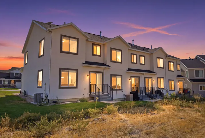 Modern coastal residence showcasing a clean-lined exterior with stucco cladding, multiple large casement windows with warm interior lighting, and a tiered roofline
