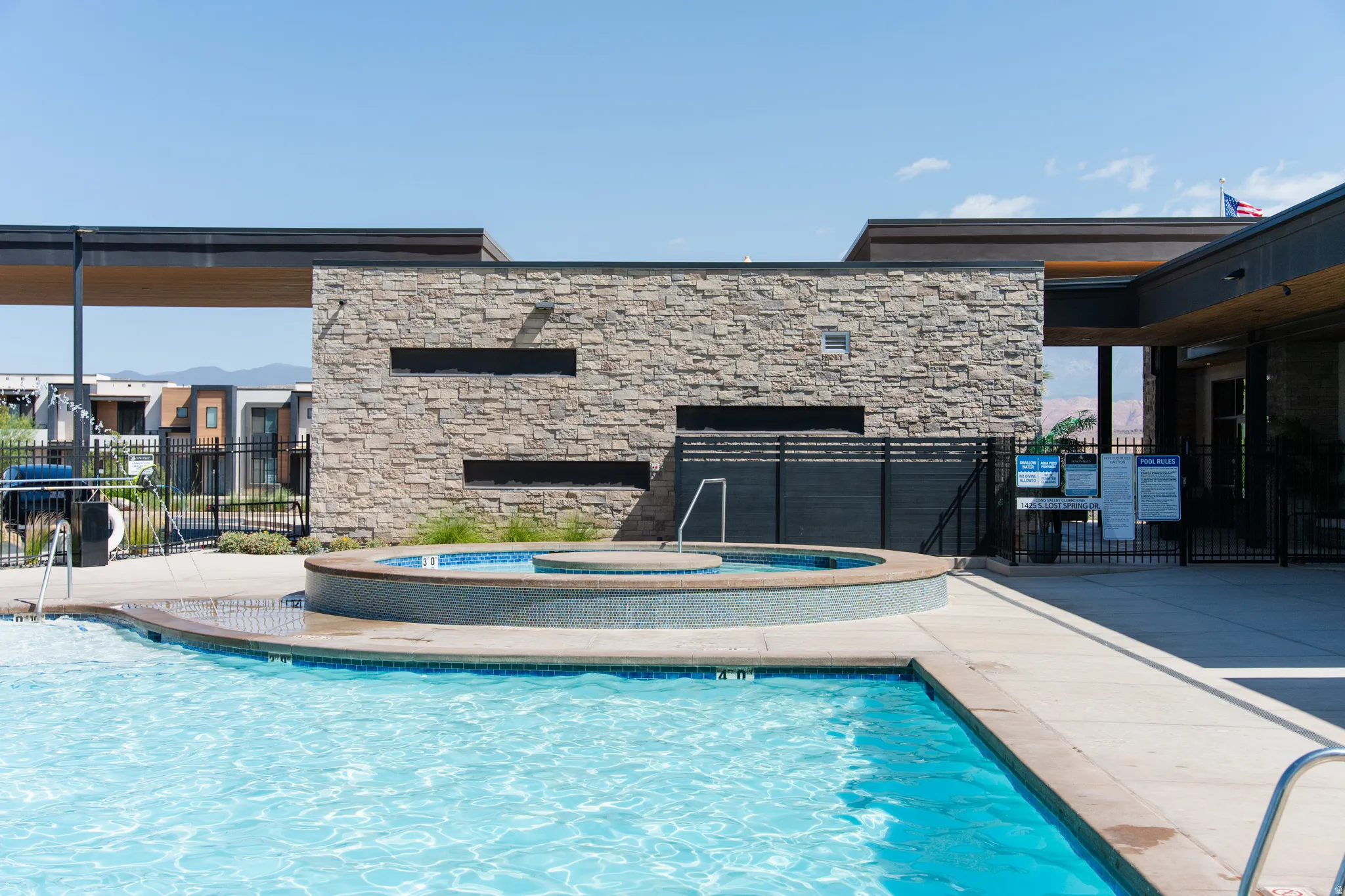 Swimming pool with an integrated hot tub and stone-clad accent wall