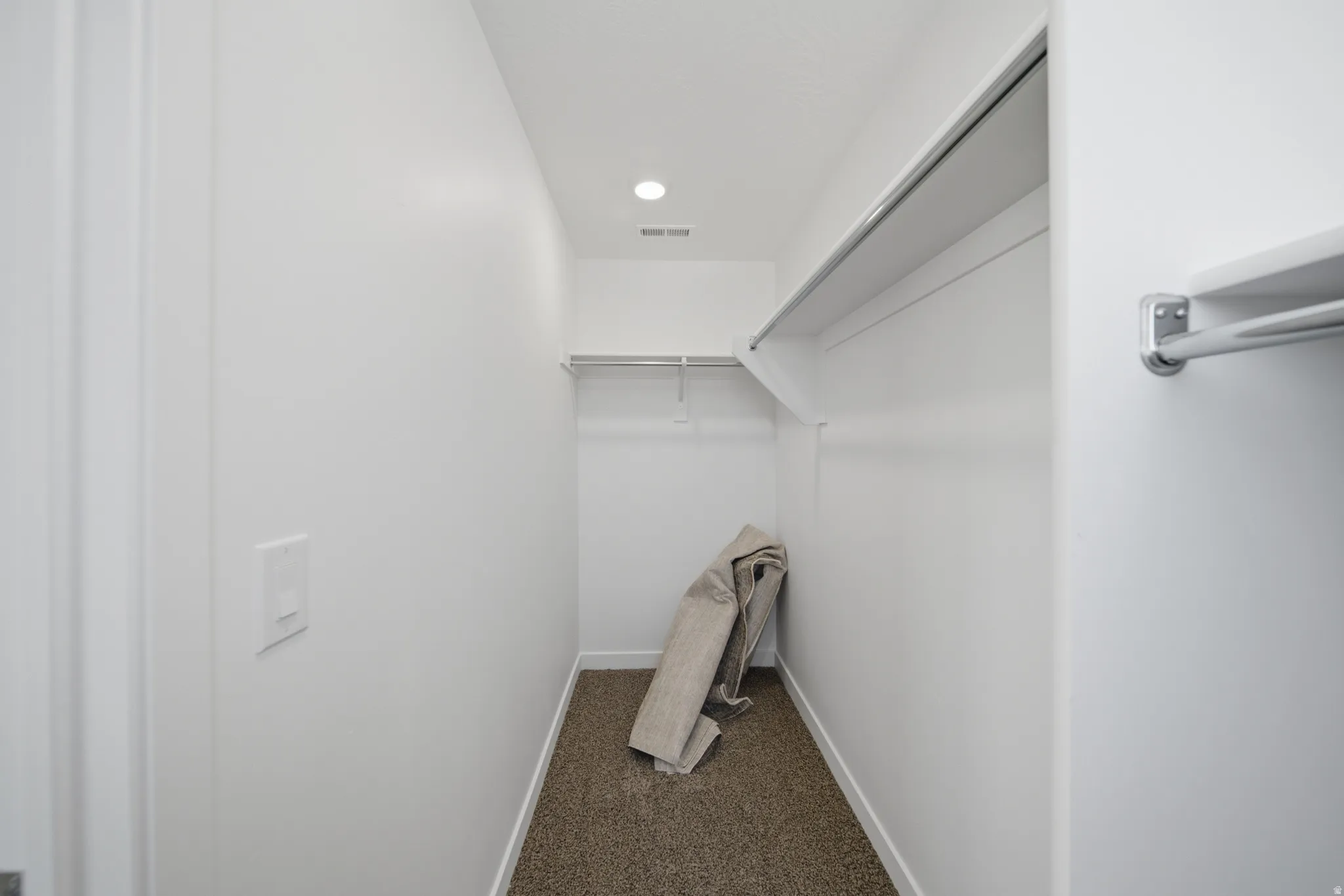 Walk-in closet featuring built-in shelving, chrome hanging rods, recessed ceiling lighting, and carpet flooring