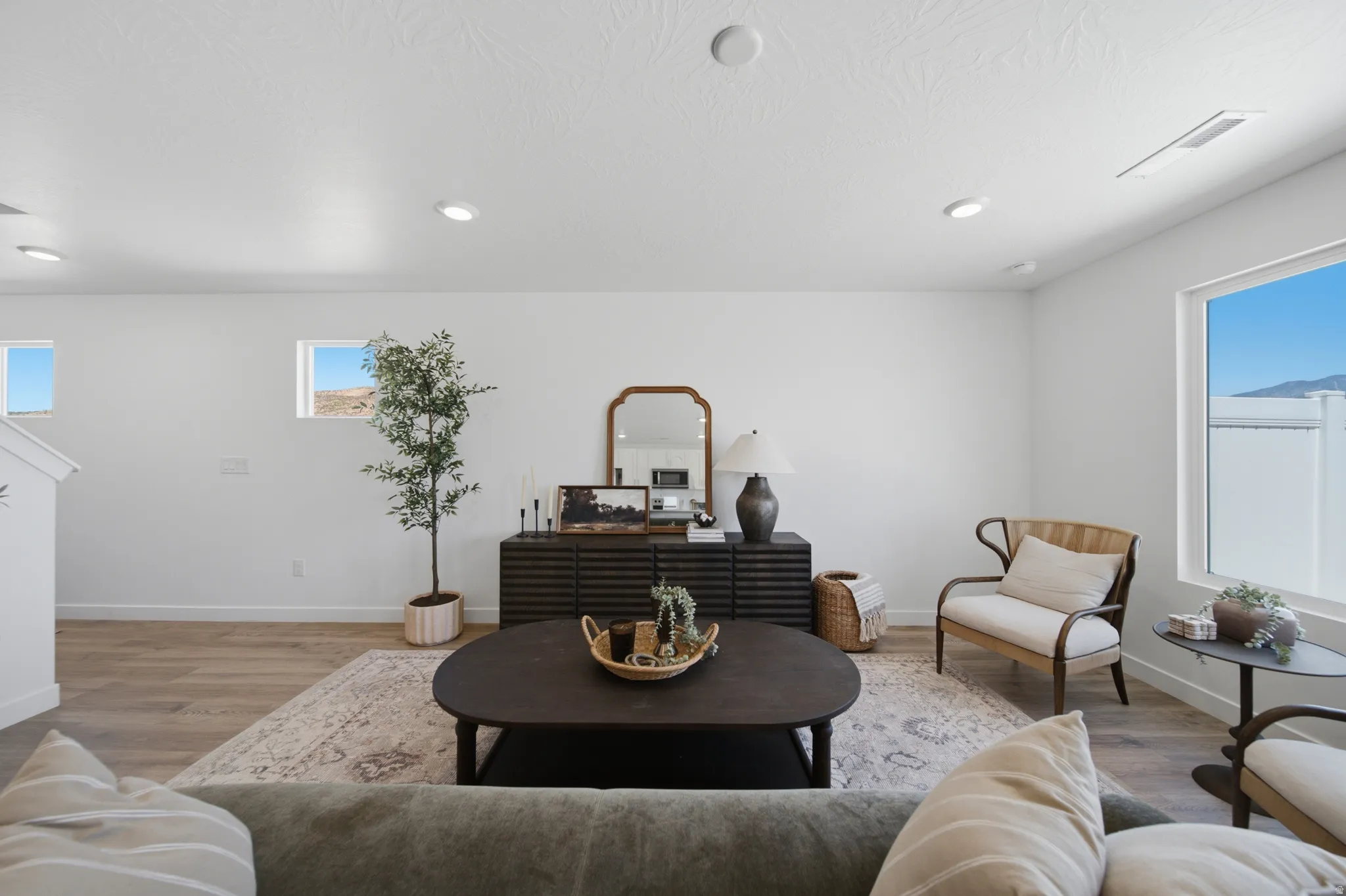 Bright living area featuring wood-finish flooring, recessed lighting, and large windows
