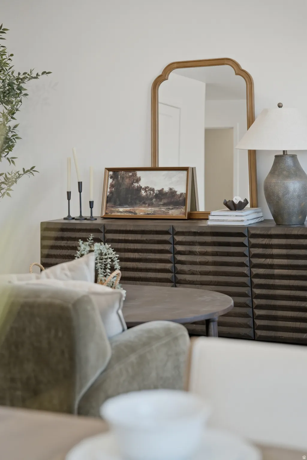 Elegant living room showcasing a horizontal-slat wood credenza with ample storage, paired with a rounded upholstered accent chair in neutral tones