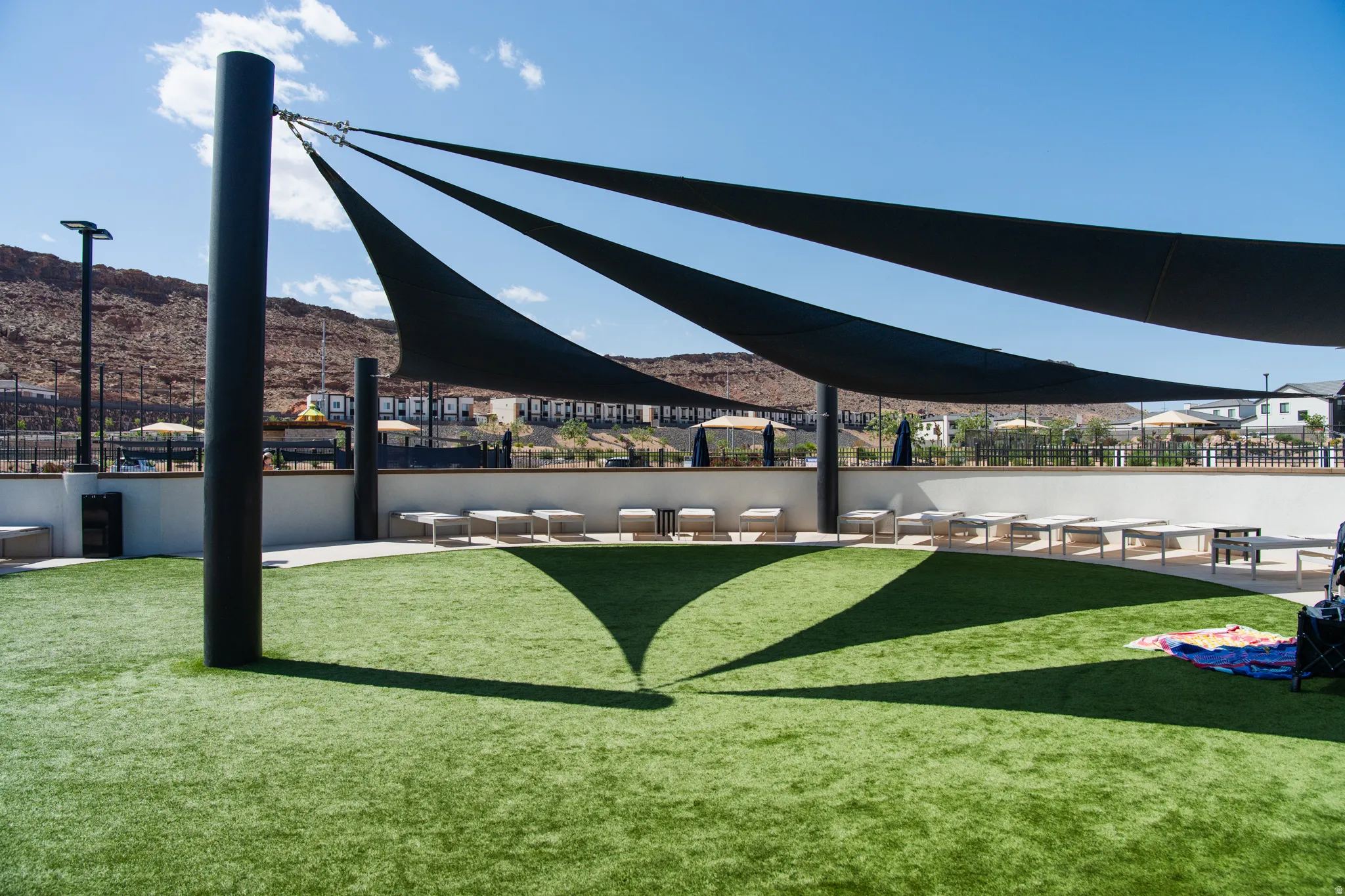 Expansive outdoor area featuring artificial turf, large shade sails, and perimeter seating