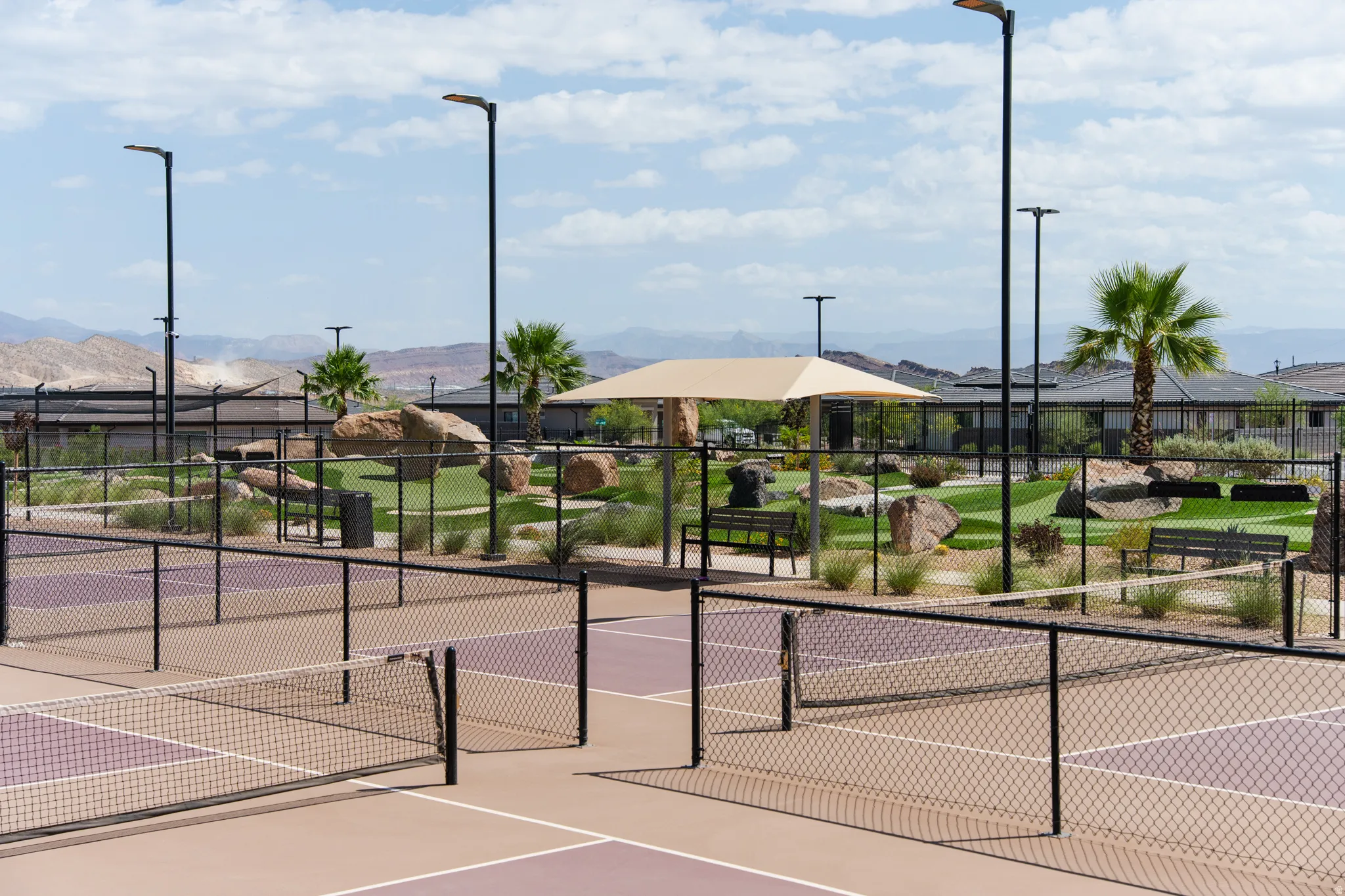 Modern pickleball courts featuring a neutral and purple playing surface, surrounded by black chain-link fencing