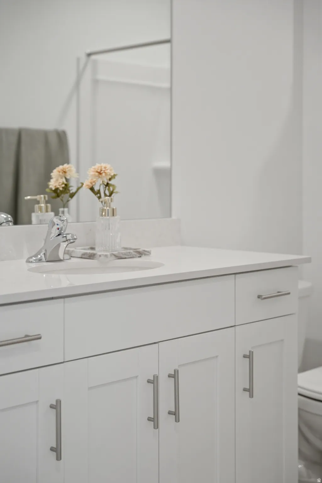 White vanity with brushed nickel hardware, integrated sink, and a countertop
