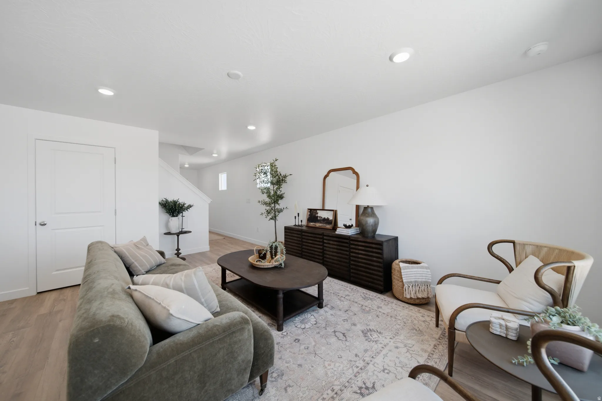 Open concept living space featuring recessed lighting, light wood-finish flooring, and a white interior door with panel detailing