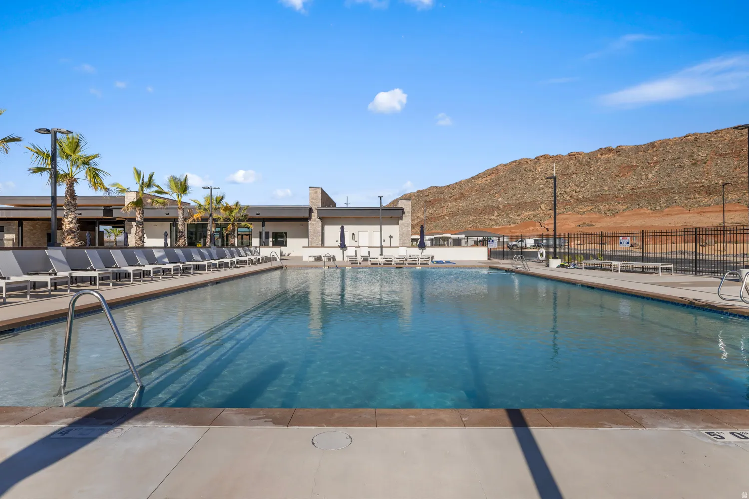 Expansive swimming pool with concrete decking, perimeter lounge seating, and a desert mountain backdrop