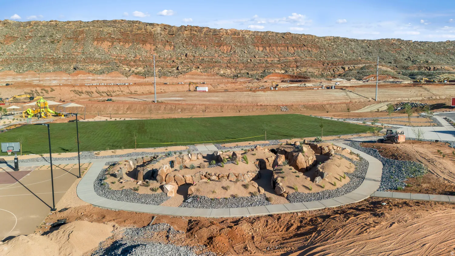 Newly constructed outdoor living space featuring a circular fire pit with natural stone surround, freshly sodded lawn area, and modern hardscape design