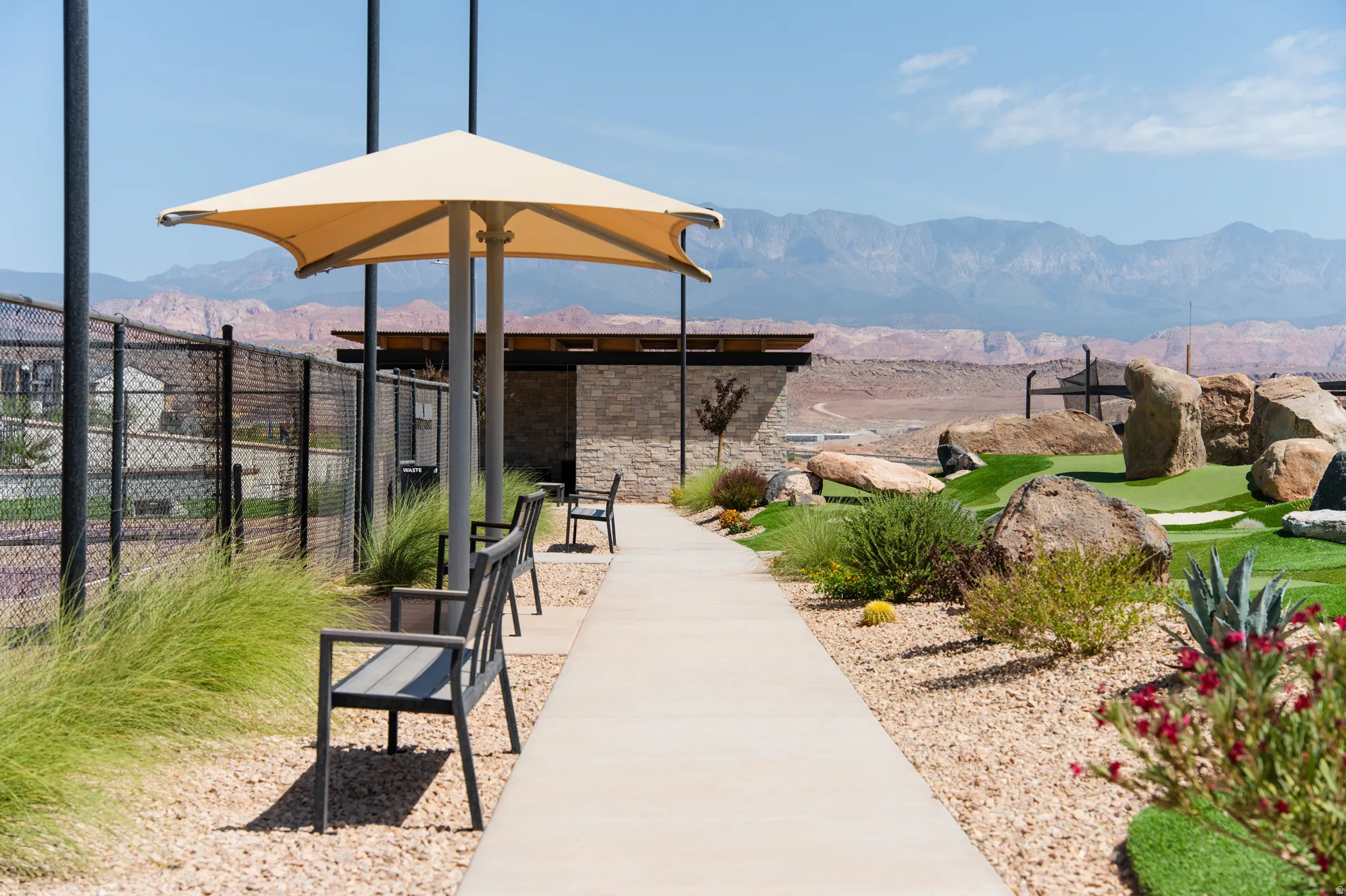 Outdoor putting green featuring artificial turf, natural rock landscaping, and desert-adapted plantings