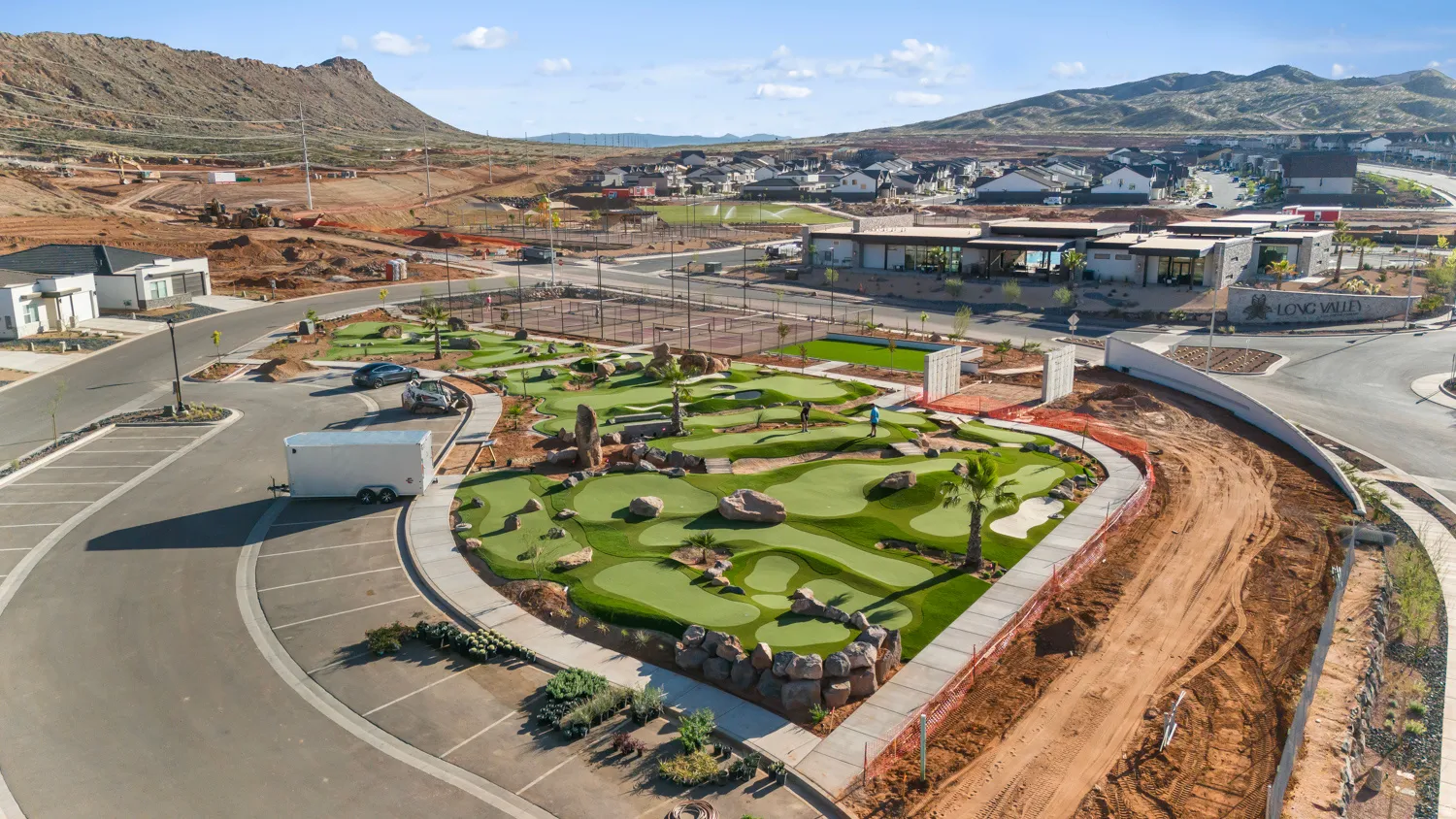 Expansive recreational area featuring a meticulously designed miniature golf course with varied terrain, multiple tennis courts, and a contemporary clubhouse building