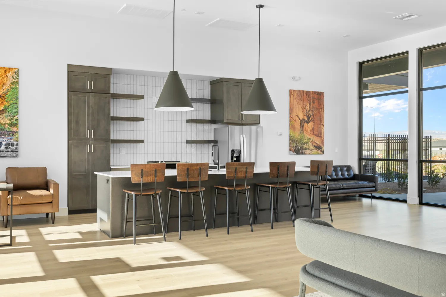 Open-concept living and dining area featuring a large kitchen island with seating for multiple guests, pendant lighting, stainless steel appliances, white subway tile backsplash, and wood-finish flooring throughout