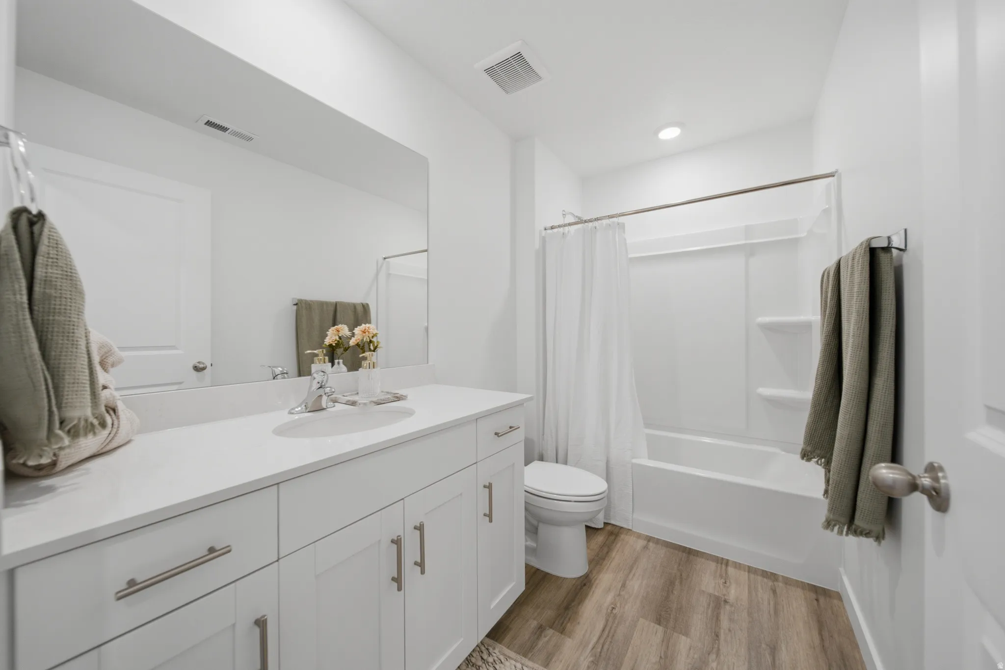 Full bathroom featuring a white vanity with slab countertop, undermount sink, and brushed nickel fixtures