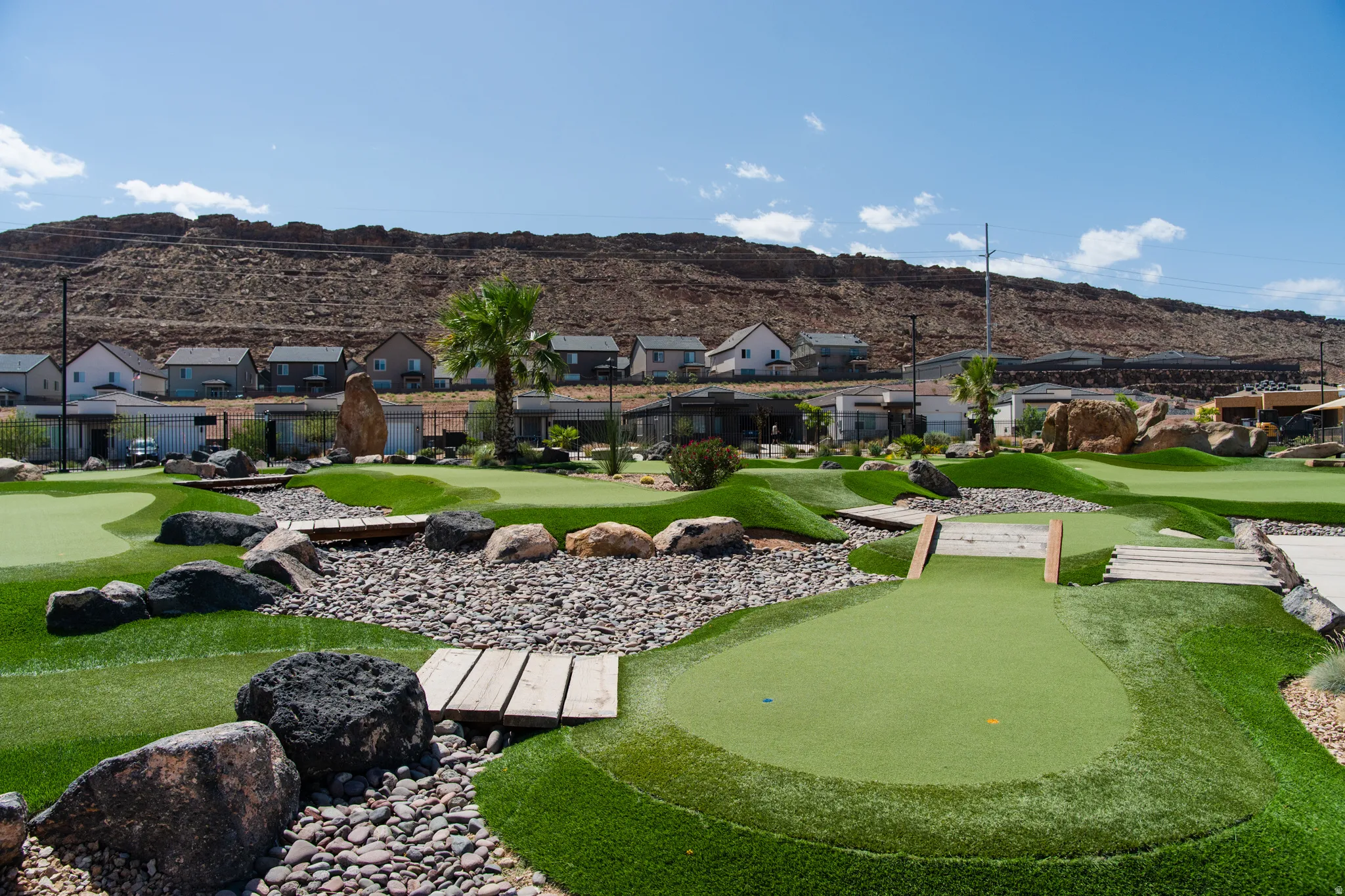 Miniature golf course featuring multiple greens, wood bridges, and rock landscaping