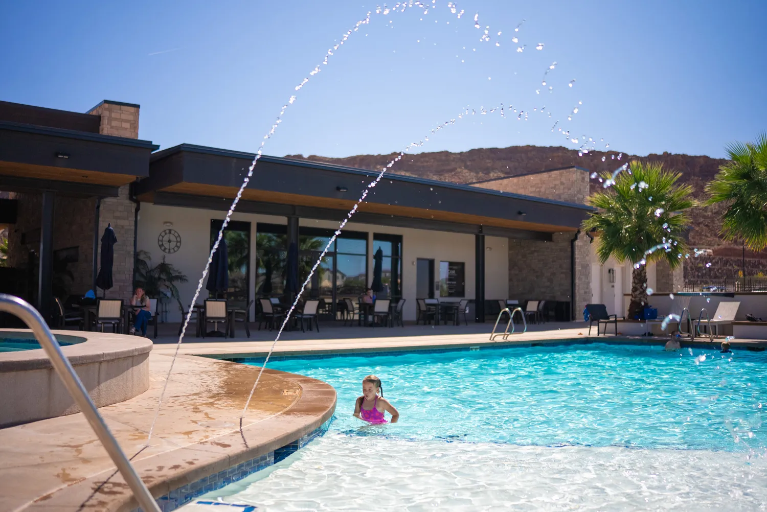 Resort-style swimming pool featuring crystal-clear waters, integrated shallow entry area, and dual water features with arching fountains