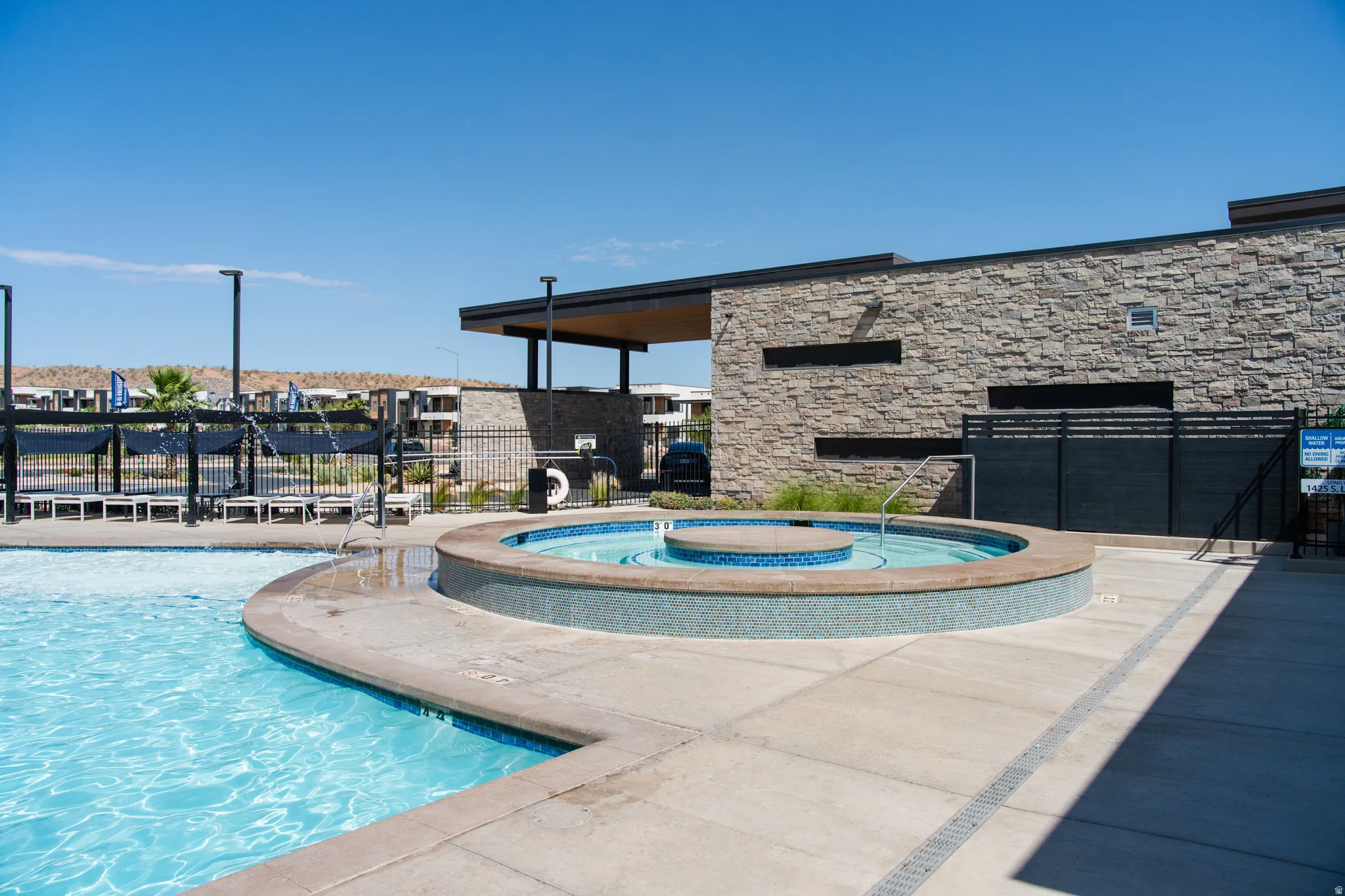 Resort-Style Pool and Spa Oasis featuring a sparkling saltwater pool with sun shelf entry, integrated hot tub with decorative tile surround, and expansive stamped concrete decking