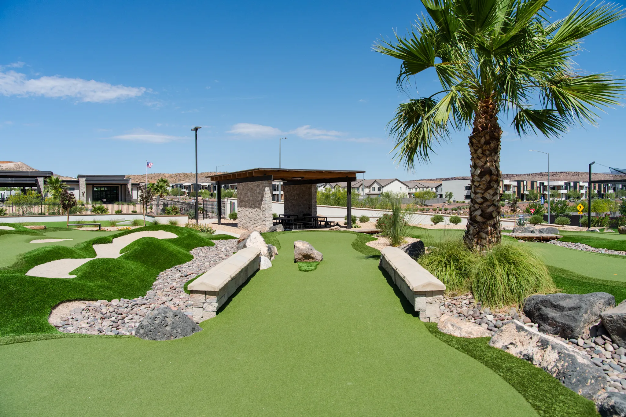 Recreational putting green with artificial turf, bordered by decorative rocks and landscaping