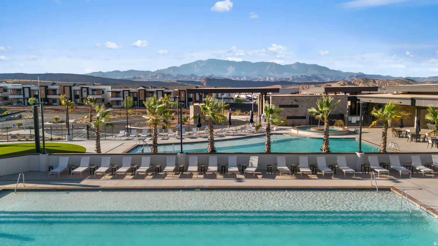 Expansive outdoor amenity area featuring multiple swimming pools with integrated steps and perimeter lounge seating